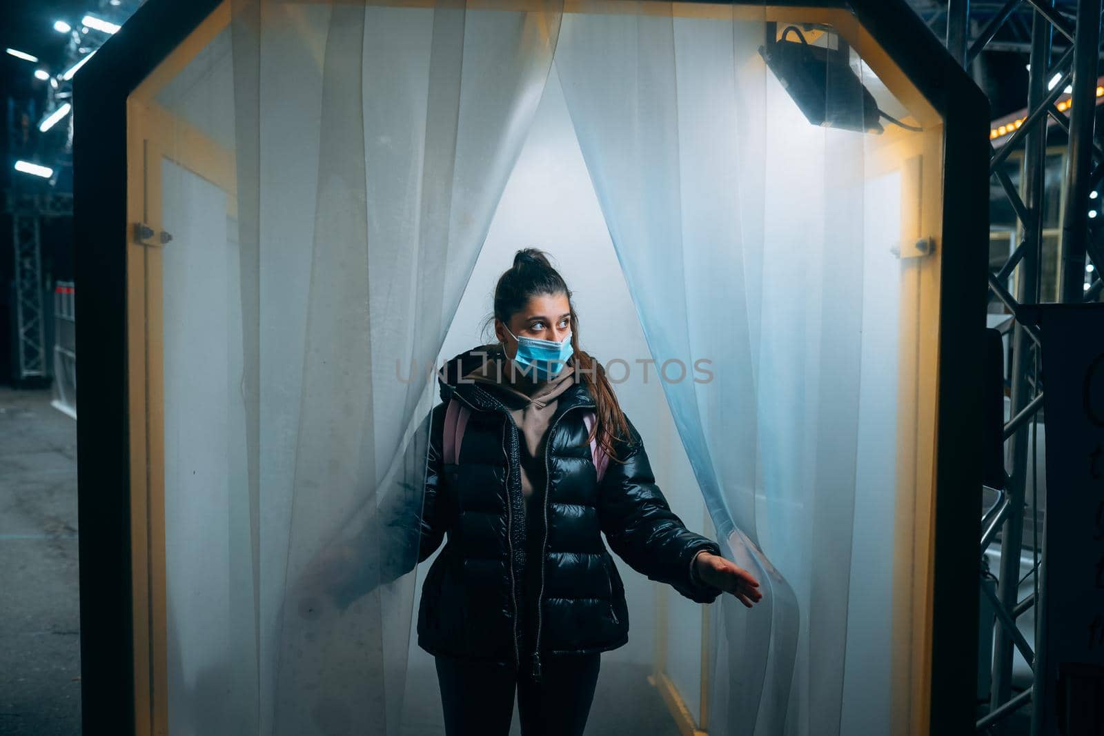 Young beautiful woman in a medic mask is staying in a disinfection tunnel