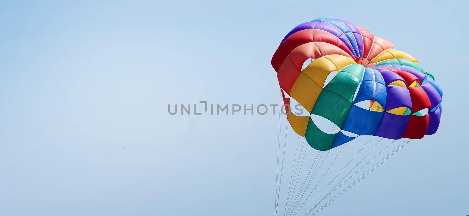 multi-colored parachute in LGBT colors as a symbol of freedom against the background of the sunny sky, copy space by Annado