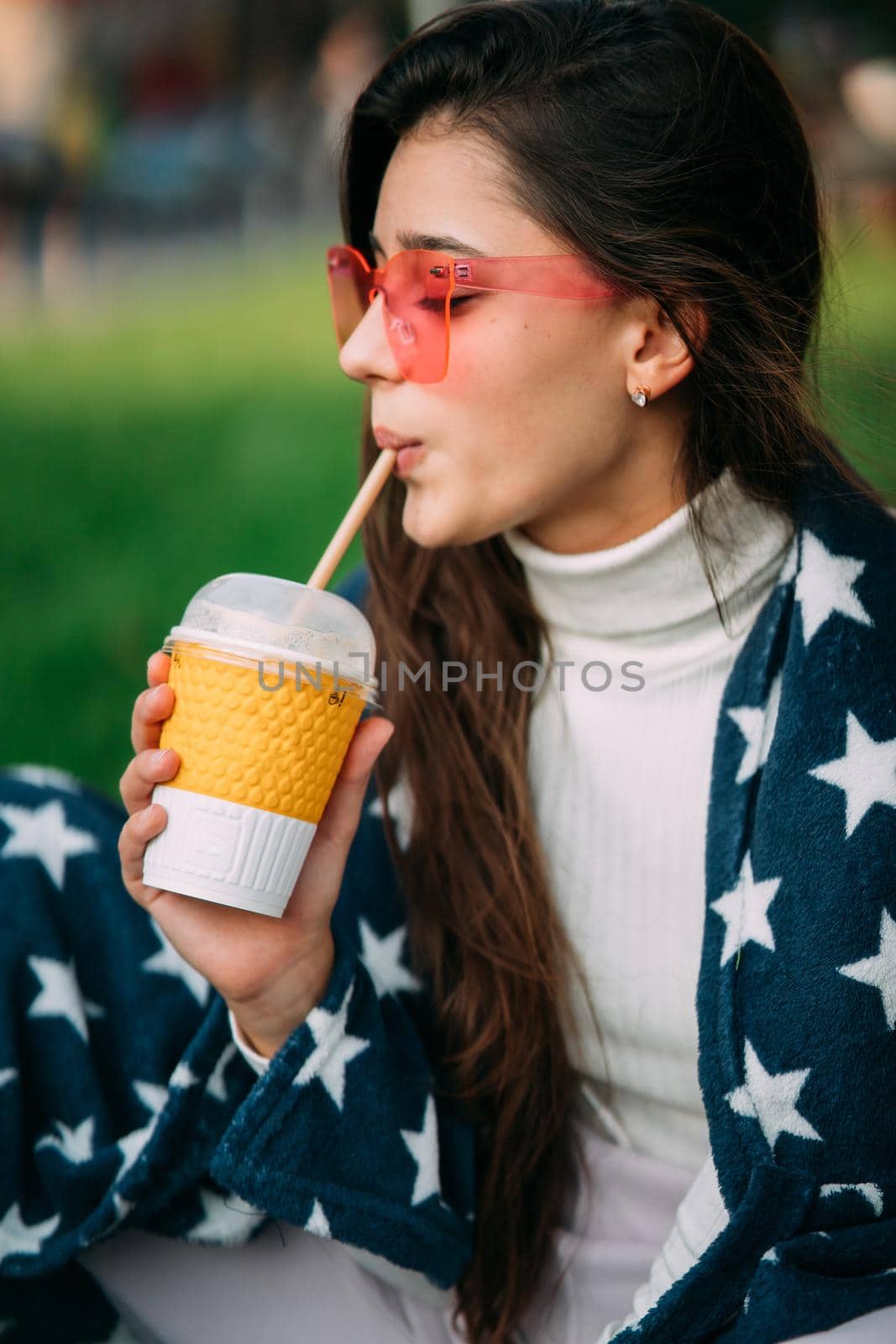 portrait of a young attractive woman in the park with a paper glass of coffee. Rest in the park