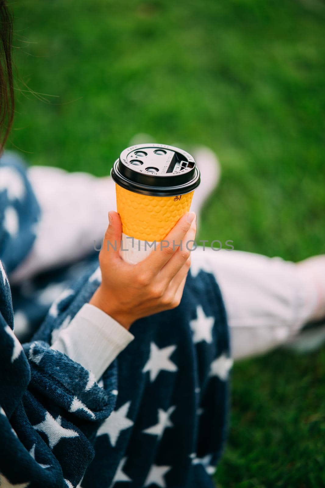 portrait of a young attractive woman in the park with a paper glass of coffee. Rest in the park