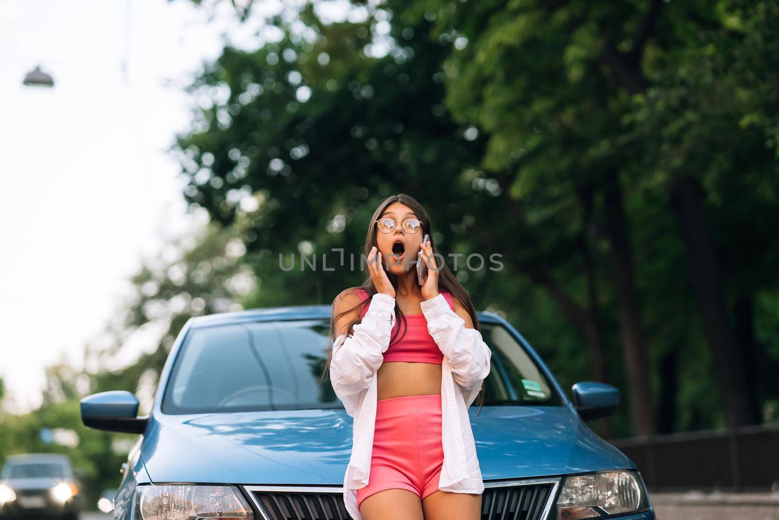 Woman talking on phone near car on road