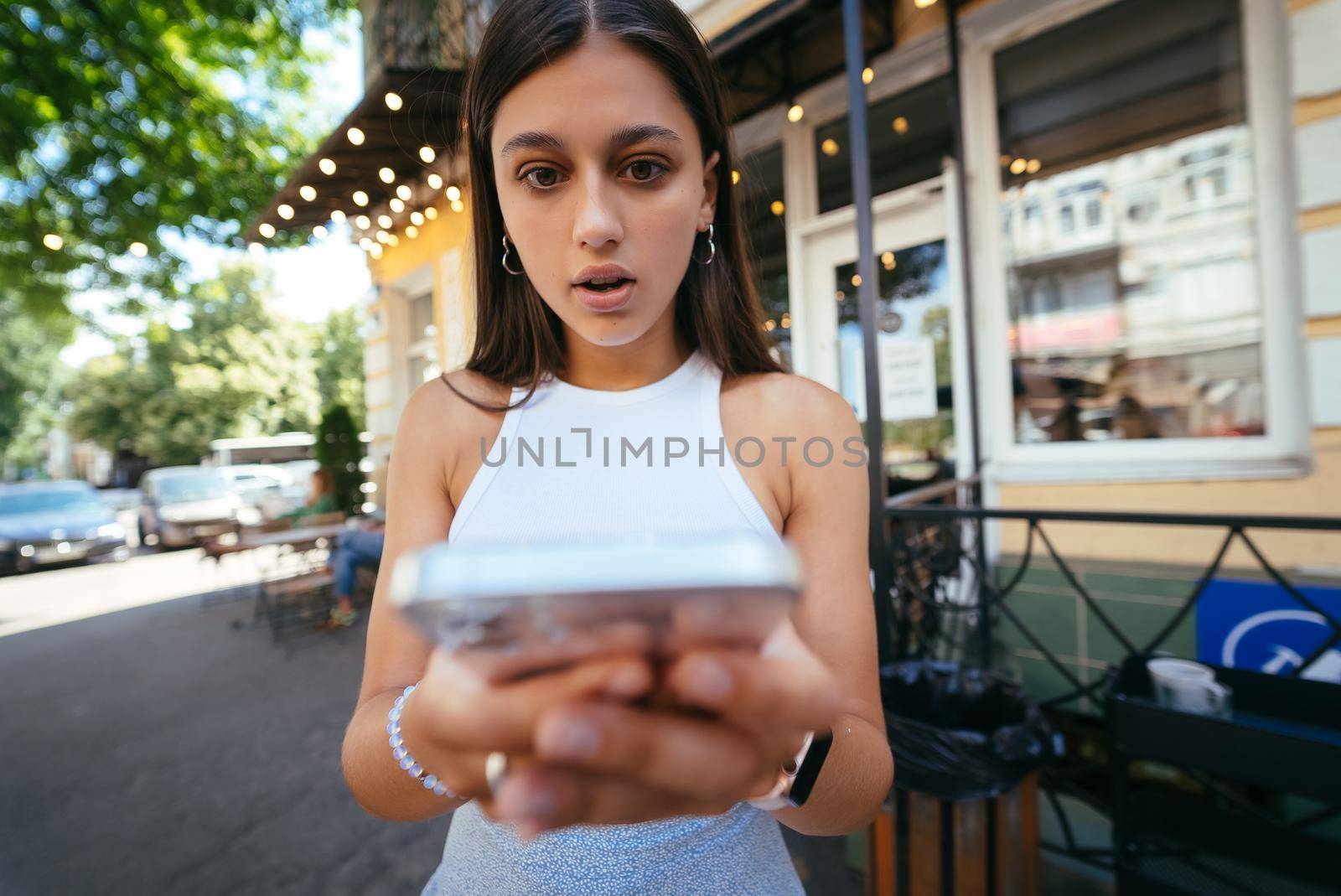 Pretty woman sitting on steps in an urban street to read an sms on her mobile phone, profile view