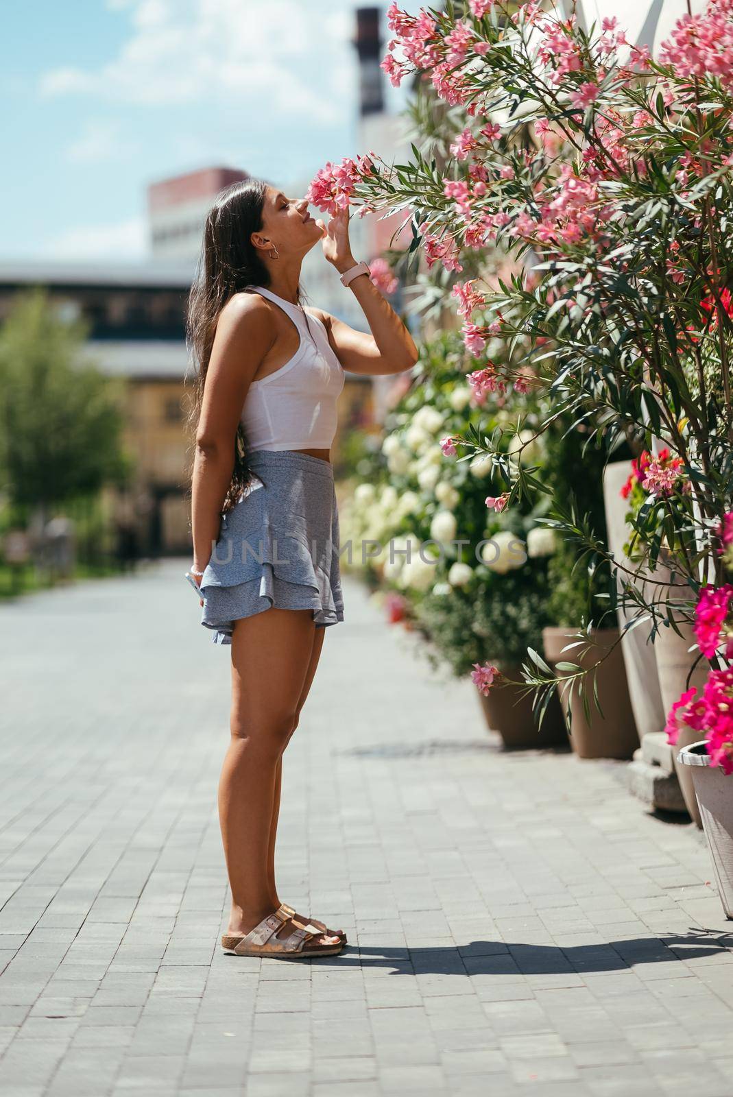Outdoor portrait of young beautiful lady posing near flowering tree. Female beauty and fashion. City lifestyle. Copy space