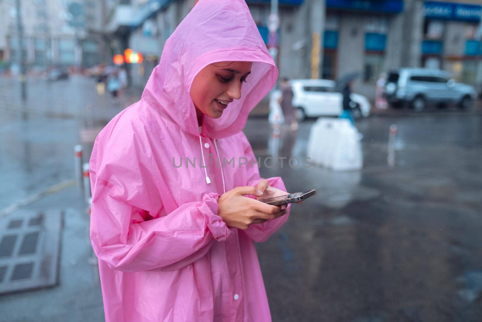 A young woman in a raincoat is waiting for someone in the rain