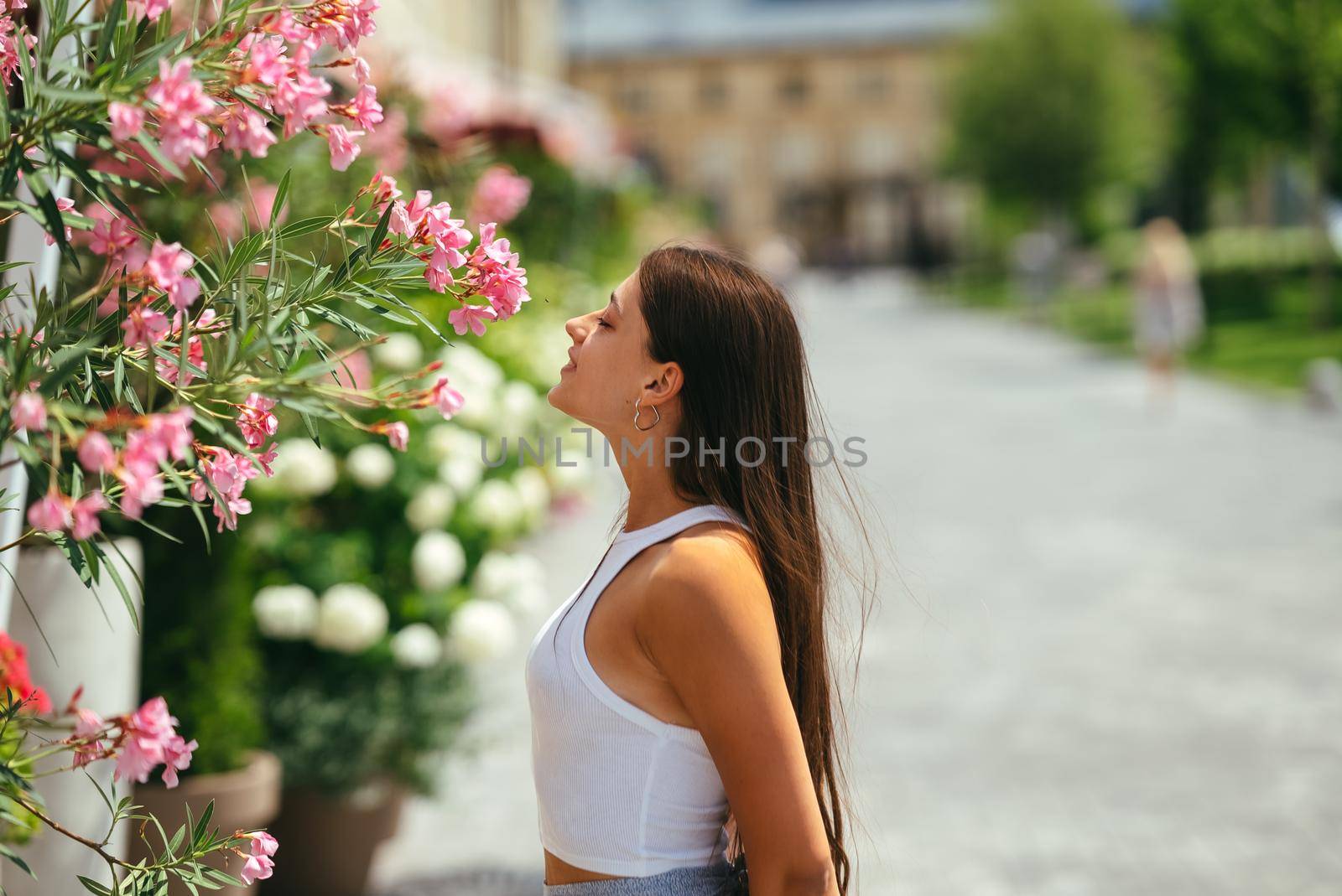 Outdoor portrait of young beautiful lady posing near flowering tree. Female beauty and fashion. City lifestyle. Copy space
