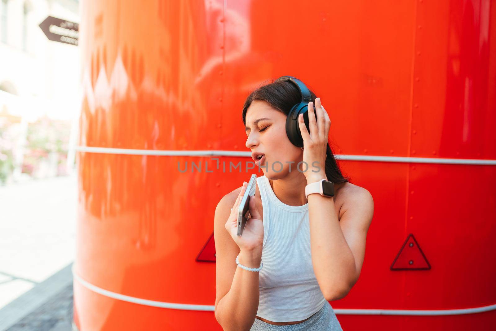 Portrait of a happy girl listening music online with wireless headphones from a smartphone in the street