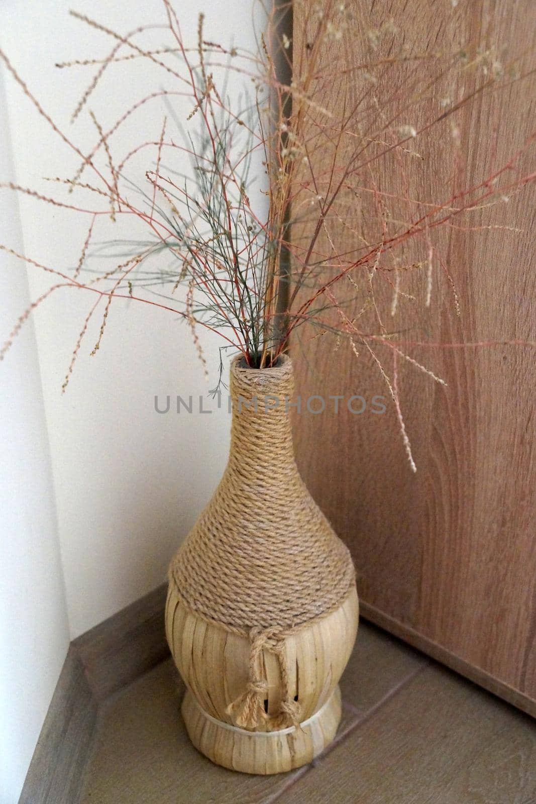 dry twigs in a decorated bottle in a vase on the floor in the interior close-up