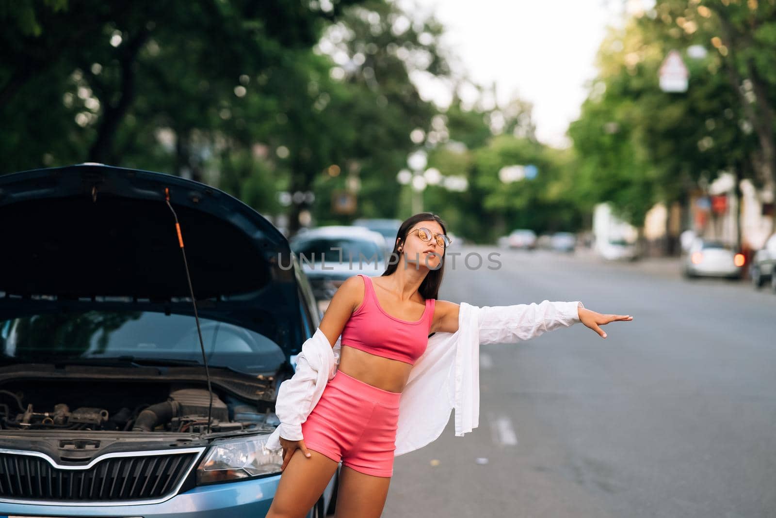 Woman with broken down car on the road she feeling serious and stressed. Look for someone help.