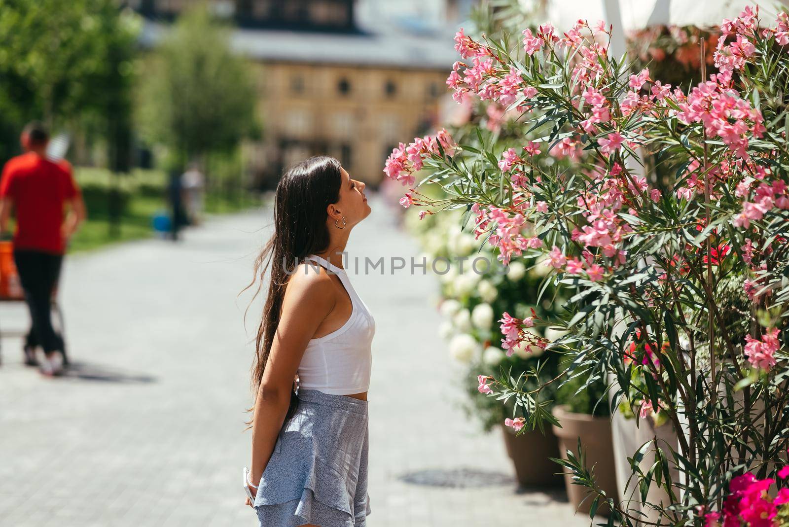Outdoor portrait of young beautiful lady posing near flowering tree. Female beauty and fashion. City lifestyle. Copy space