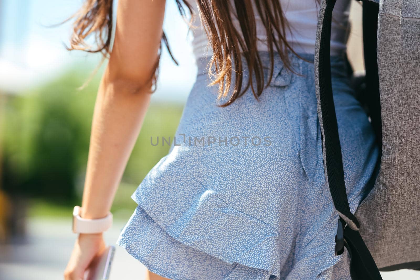 Urban young hipster woman with stylish backpack walks around the city near a building in the spring day. Pretty girl travels.