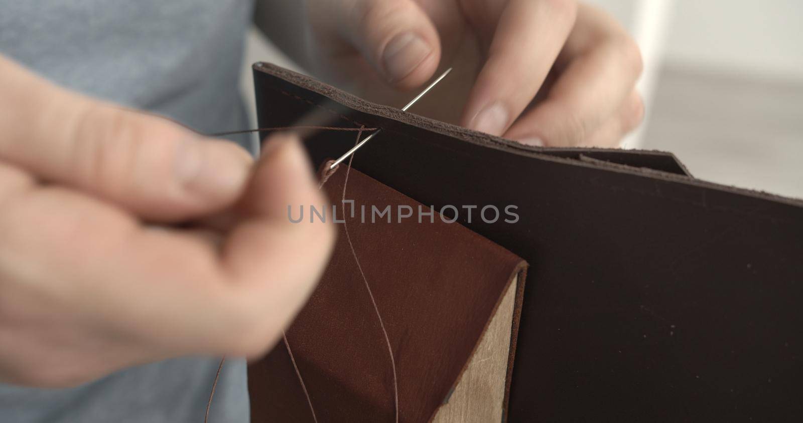 Working process of stitching a brown leather wallet by needle in the leather workshop