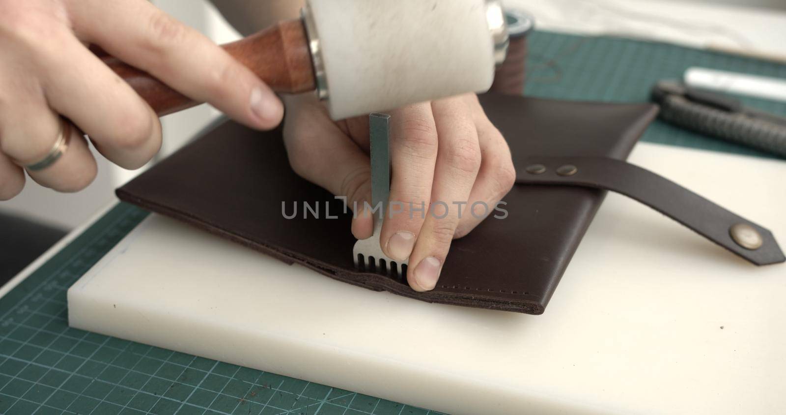 Making of brown handmade leather wallet. Sewing wallet. Piercer punches holes in a piece of skin