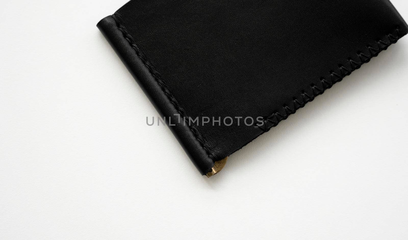 Black men's money clip handmade leather wallet for cards lies on a white table. Leather goods and accessory. by vovsht