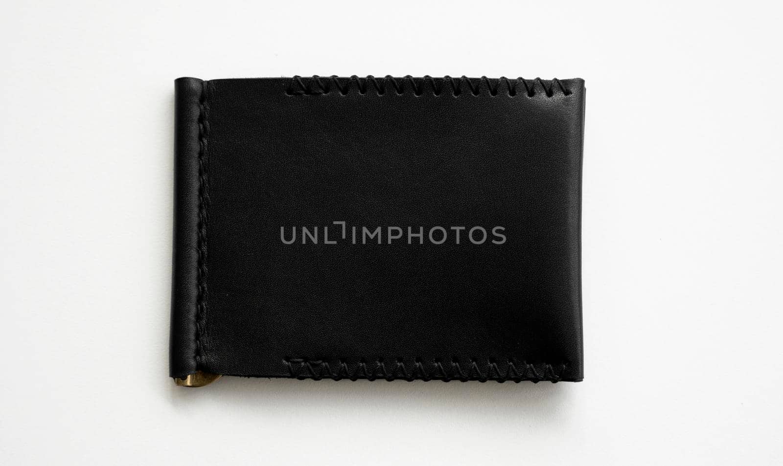 Black men's money clip handmade leather wallet for cards lies on a white table. Leather goods and accessory. by vovsht