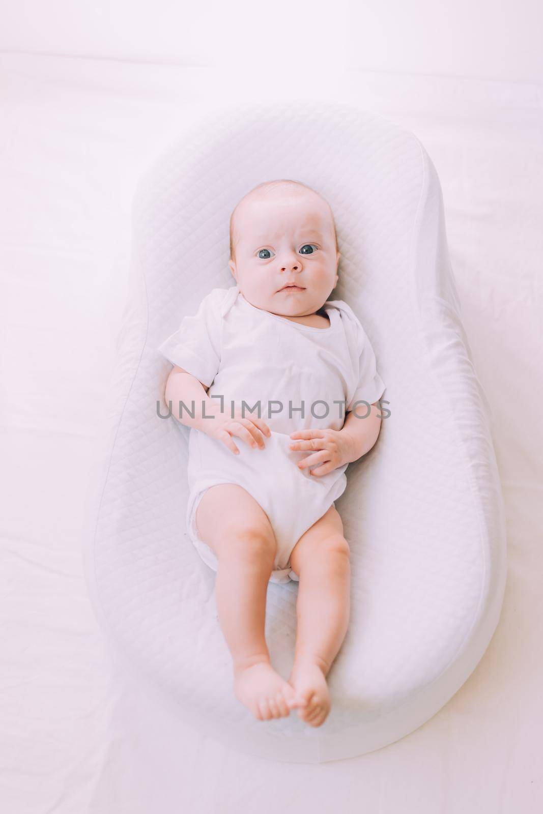 The baby is lying in a cocoon of copy space . The baby is 0-3 months old. A contented infant. An article about choosing a cocoon for newborns. An article about the benefits of cocoon. An article about colic . White background. by alenka2194