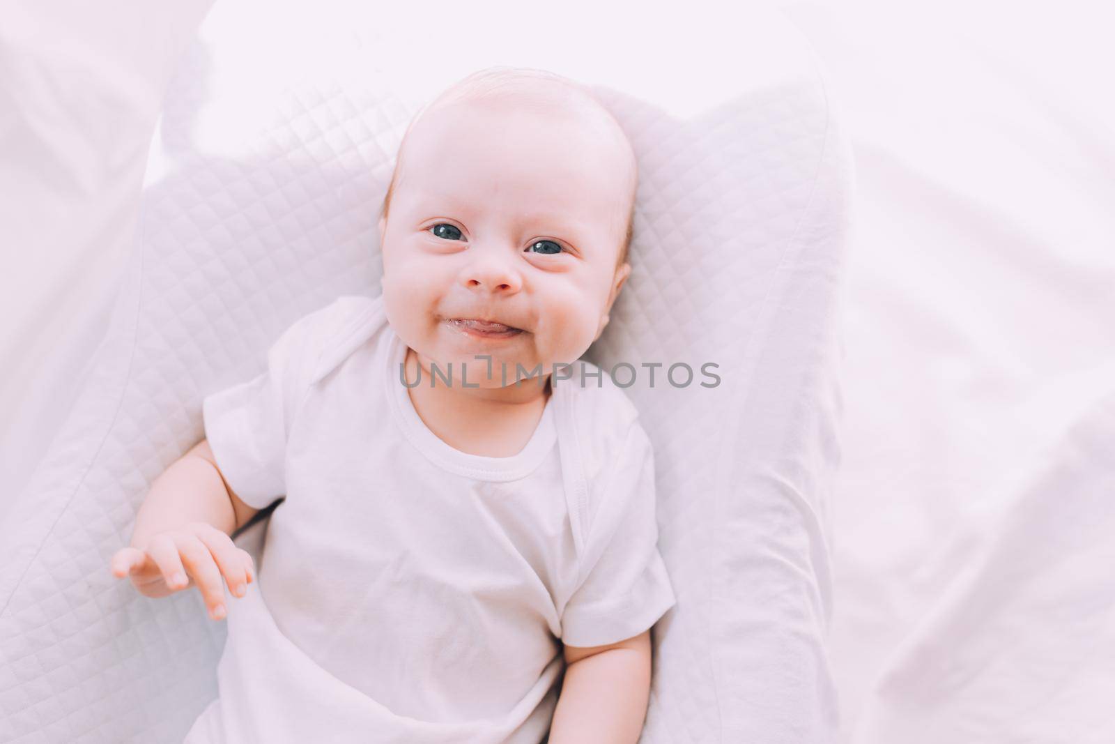 The baby is lying in a cocoon of copy space . The baby is 0-3 months old. A contented infant. An article about choosing a cocoon for newborns. An article about the benefits of cocoon. An article about colic . White background. High quality photo