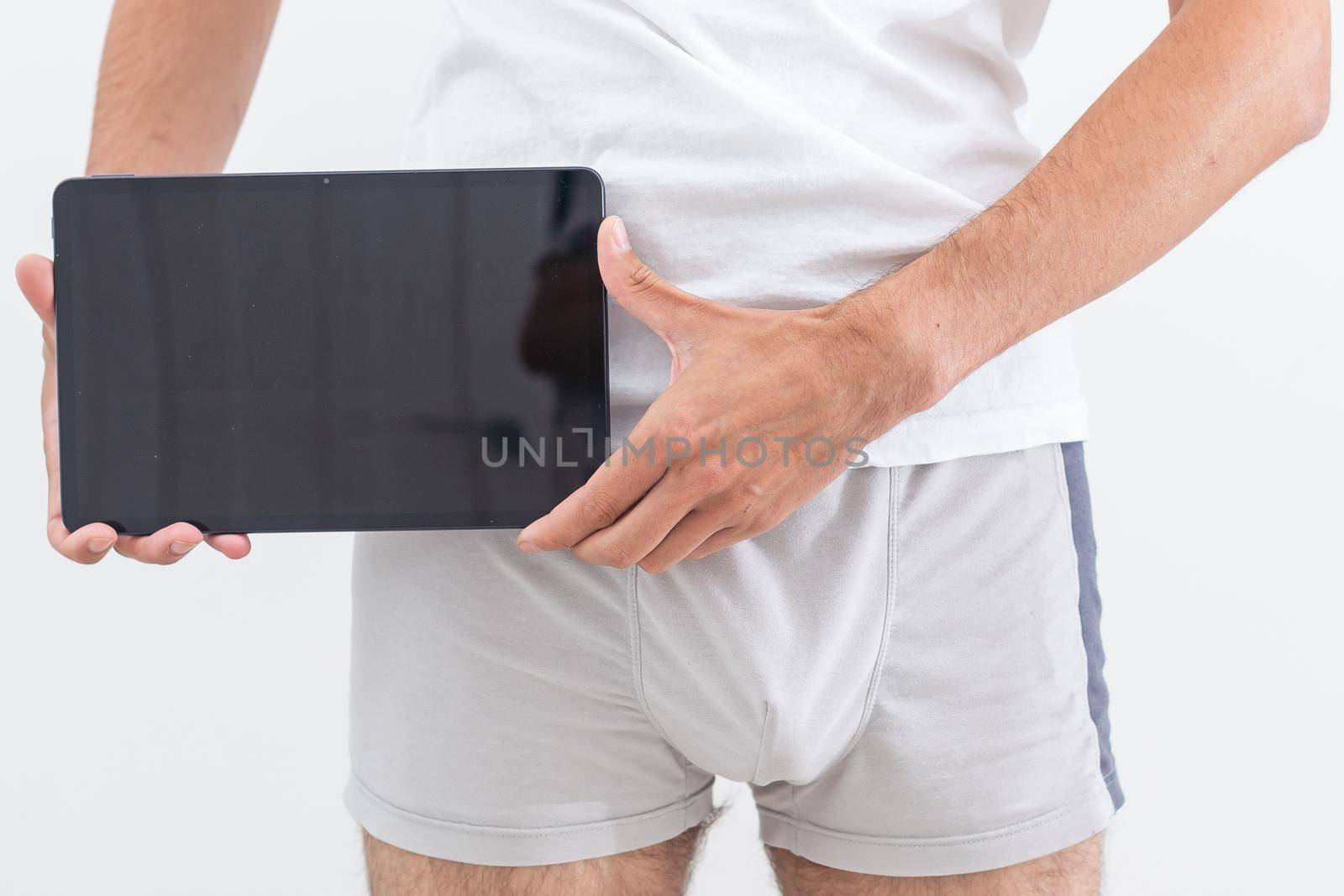 a man in underwear is holding a tablet.