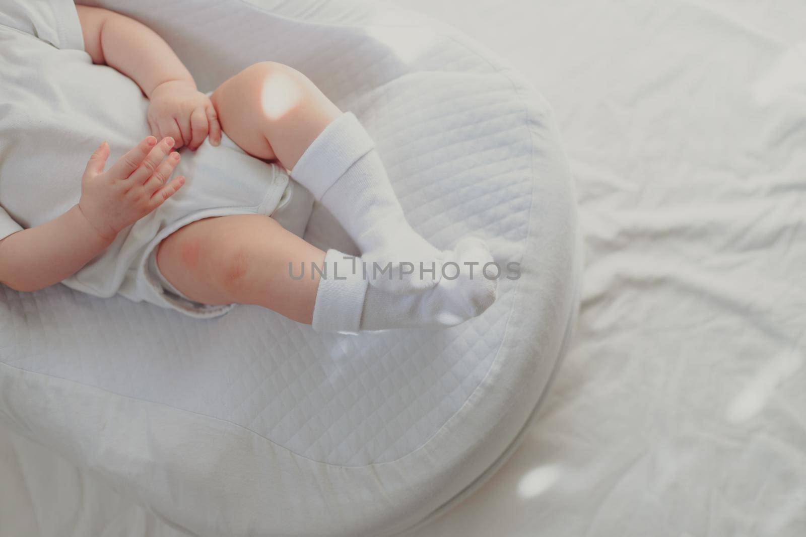 The baby is lying in a cocoon of copy space . The baby is 0-3 months old. A contented infant. An article about choosing a cocoon for newborns. An article about the benefits of cocoon. An article about colic . White background. by alenka2194