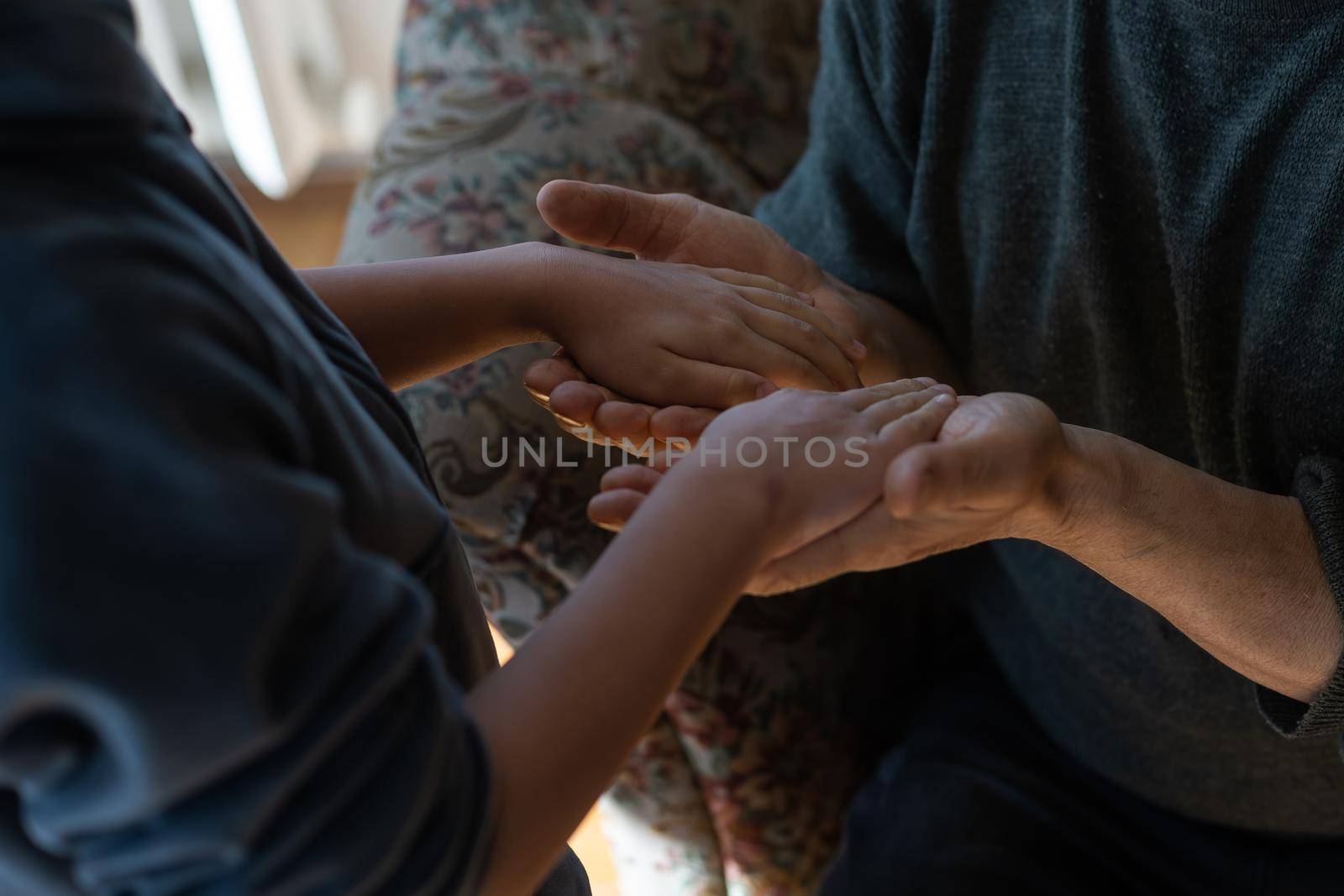 the hands of the child embracing a hand of the old man.