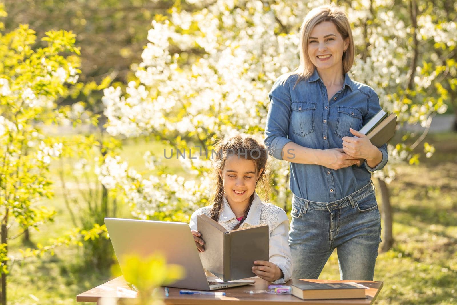 little girl with mom learning on laptop outdoor.