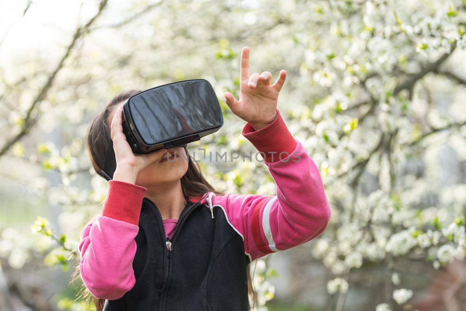 Full body little girl excited and entertained, playing with virtual reality glasses, exploring a fantasy world, trying to touch something. by Andelov13