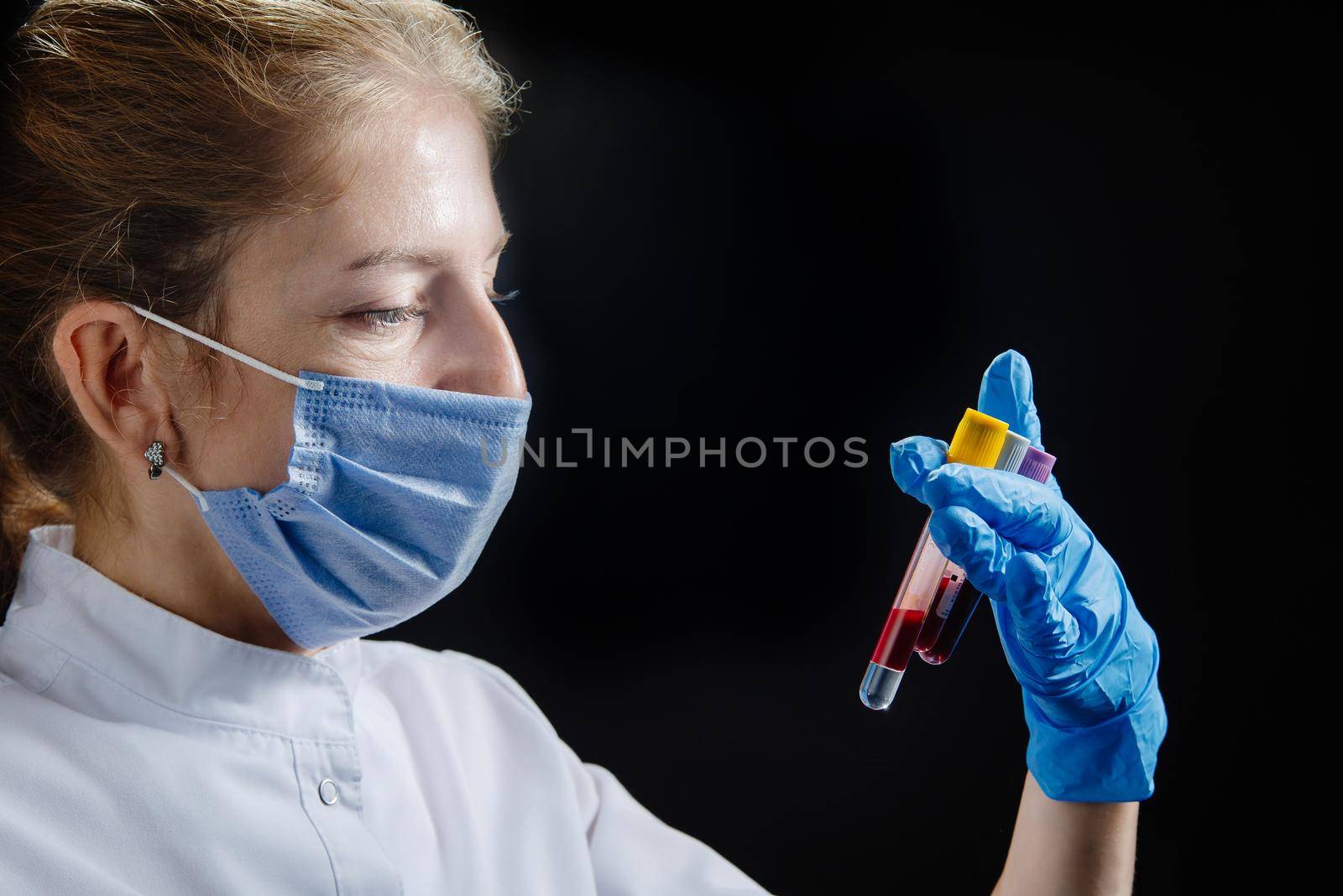 A medical worker is a doctor or nurse who works late. A female doctor is holding test tubes and examining them.