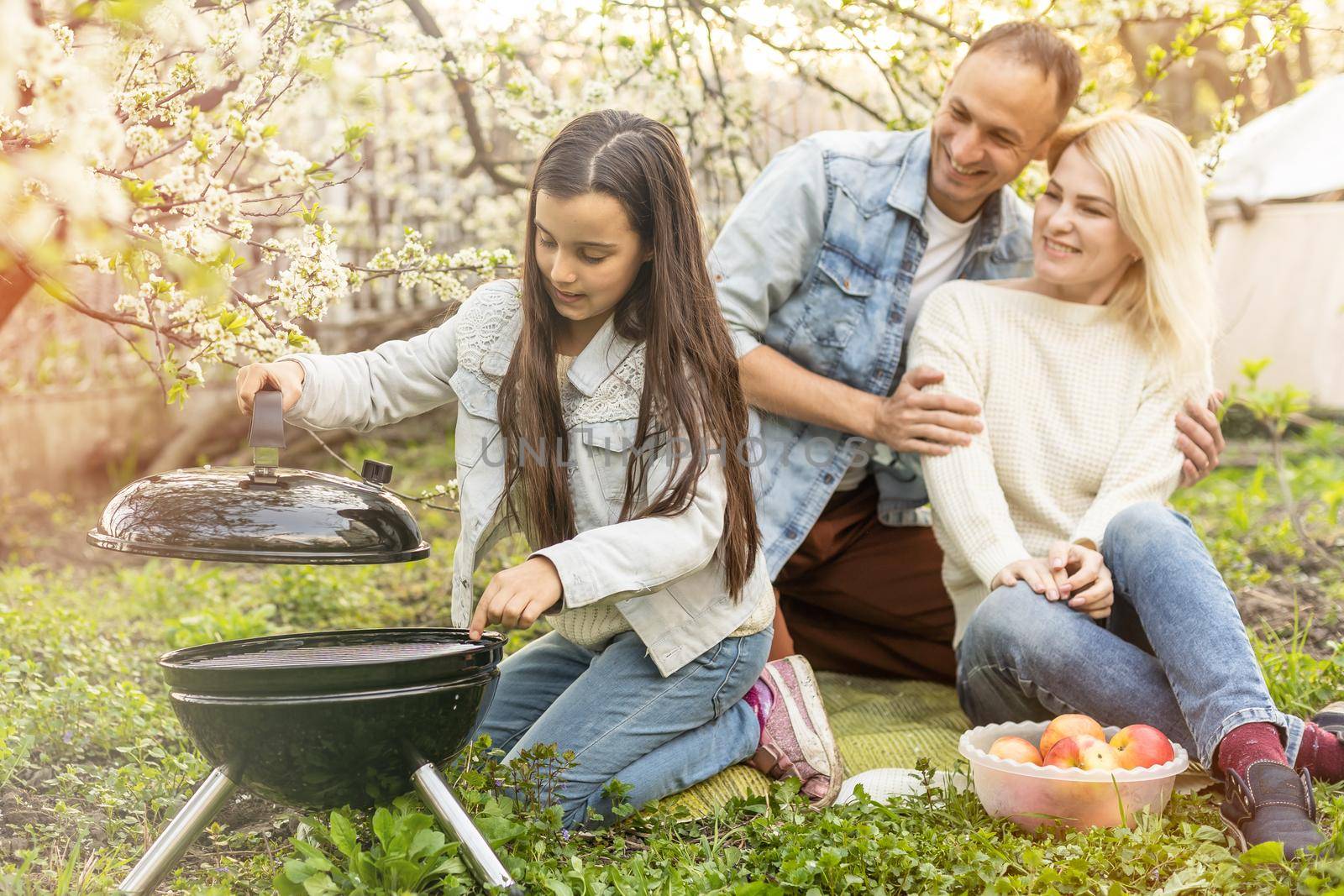 smiling parent grilling meat with daughter on camping.