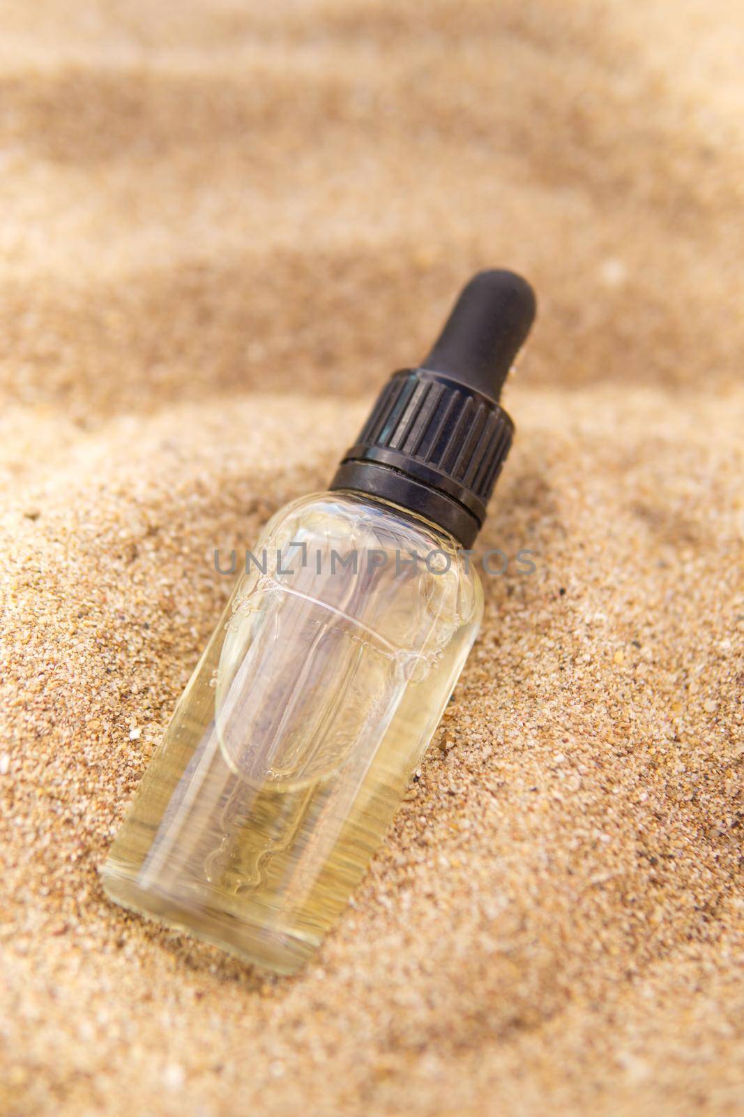 Cosmetic serum in a glass bottle with a pipette in the sand by Annu1tochka