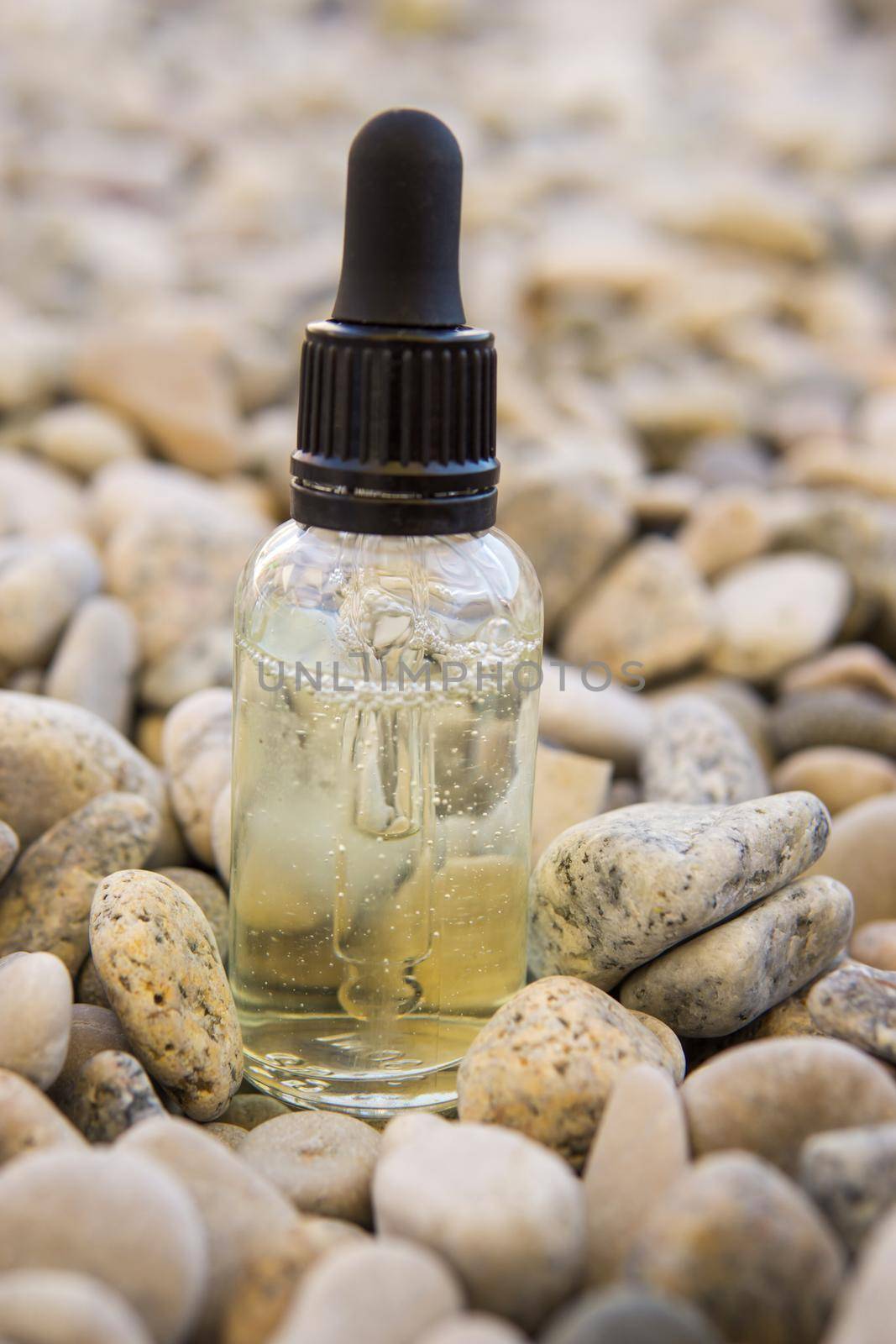 Cosmetic serum in a glass bottle with a pipette on stones by Annu1tochka