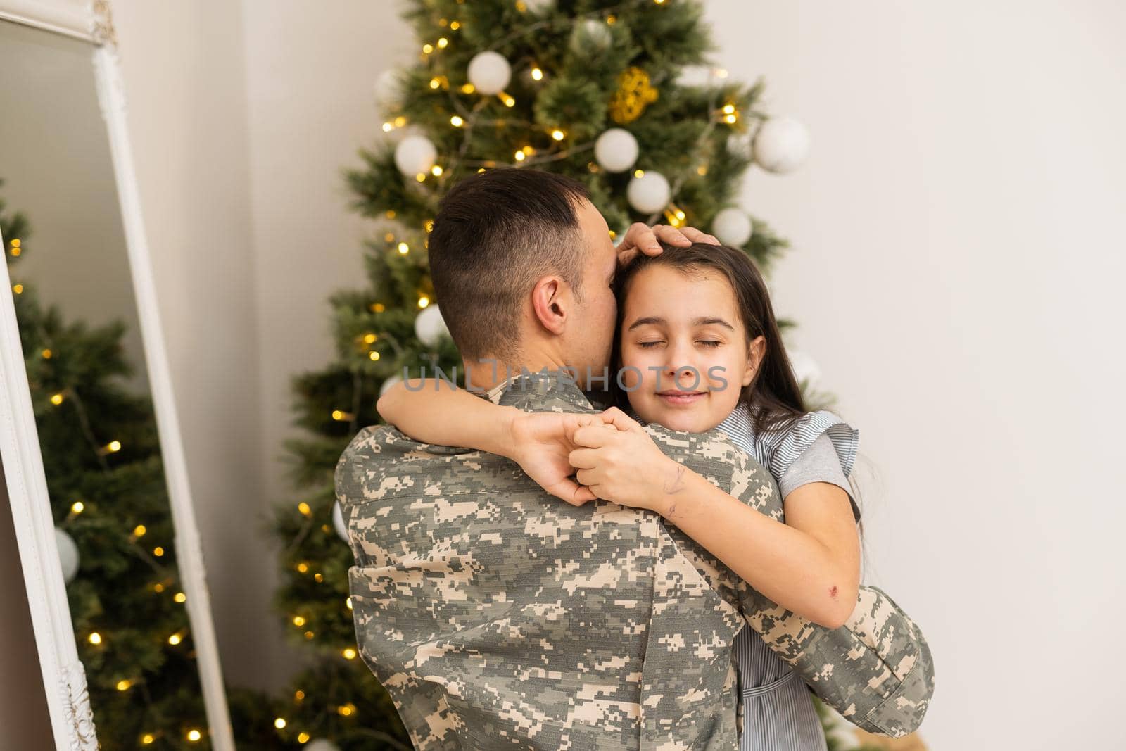 Armed Forces Soldier Hugging his daughter In Front Christmas Tree. by Andelov13