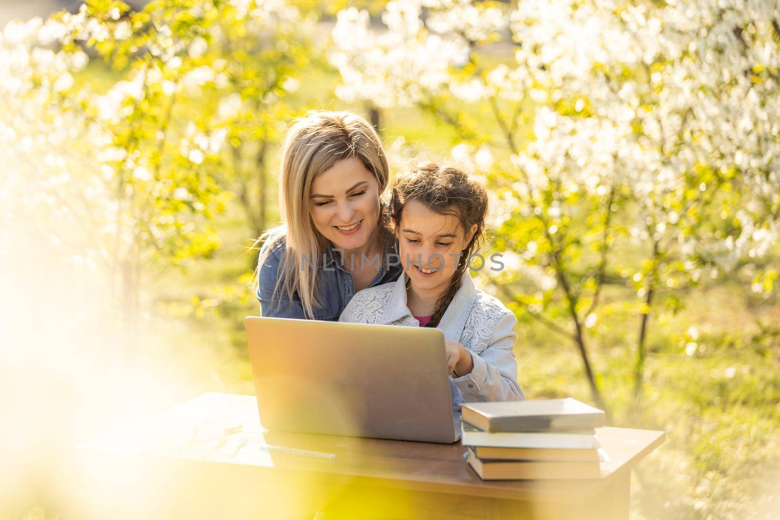 Mother daughter spending time outside. Mom and kid using laptop in nature by Andelov13