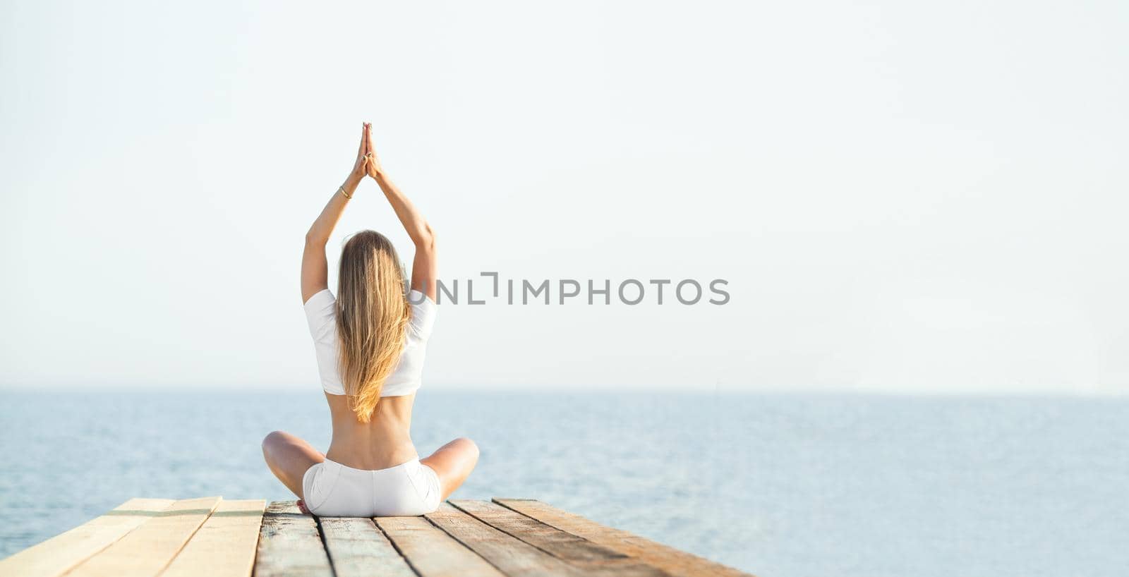 Beautiful positiveblond girl practicing yoga at seashore and meditating by MikeOrlov