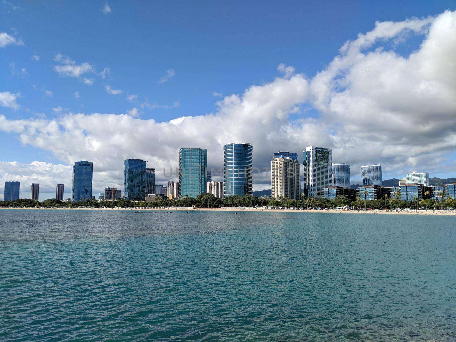 Waters and beach of Ala Moana Beach Park with office building and condos in the background during a beautiful day on the island of Oahu, Hawaii. 