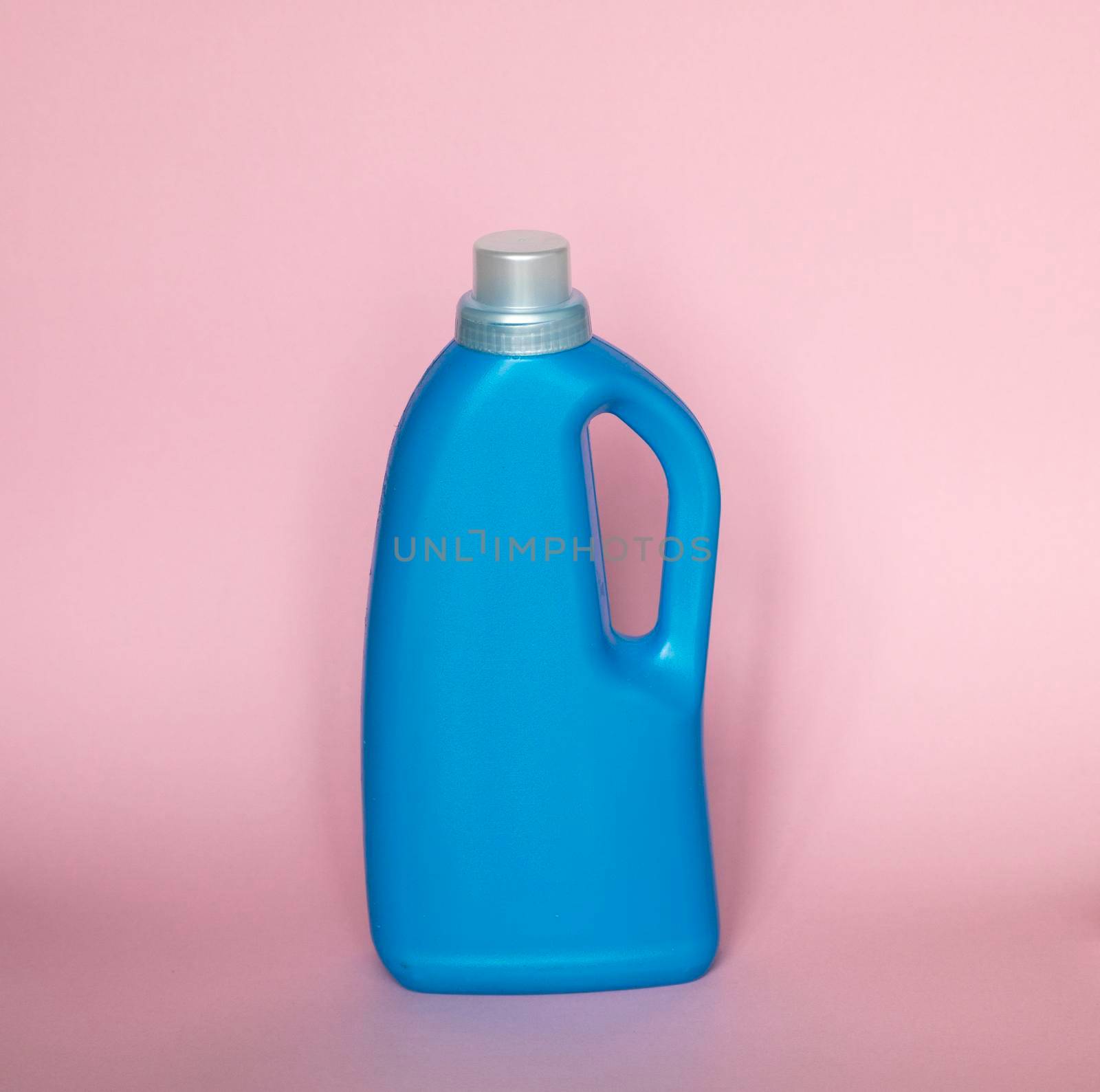 Blue plastic bottle with a grey cap isolated on pink background for liquid detergent laundry or cleaning agent. Packaging template mockup. by vovsht