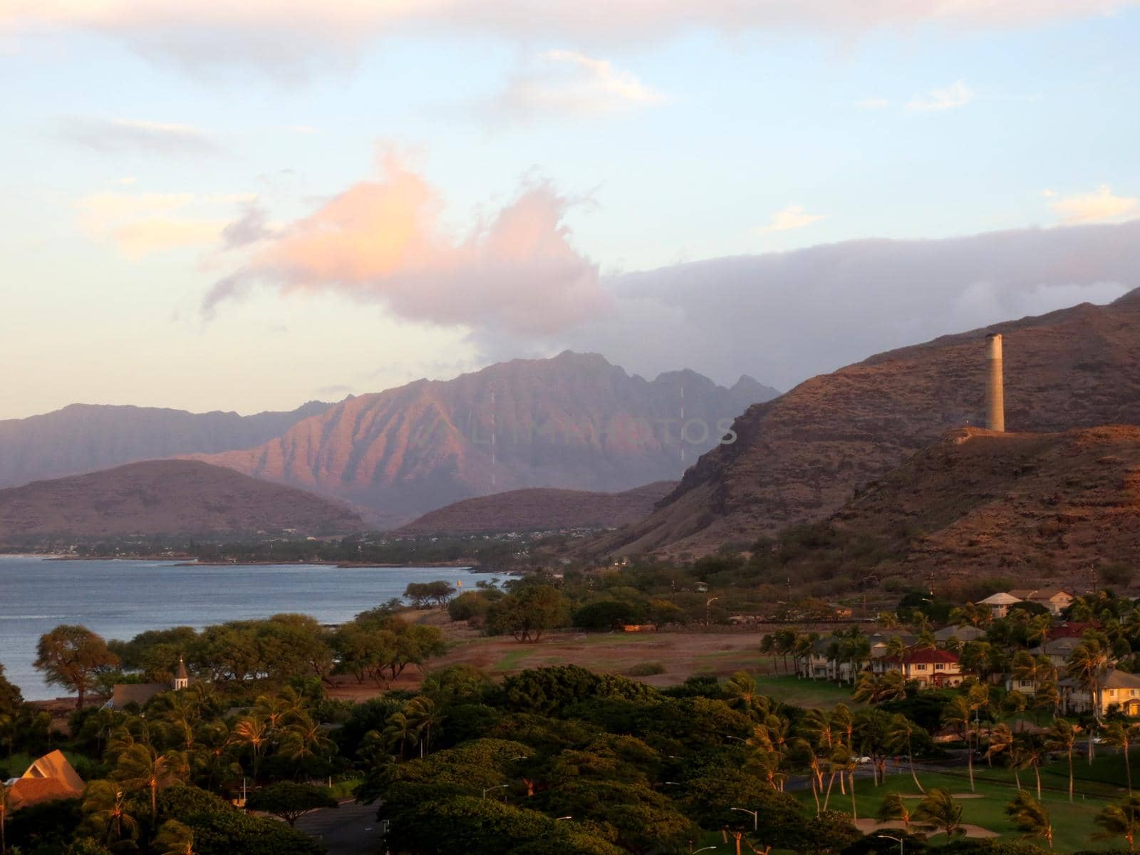 Ko Olina and the Waianae Coast with Mountains in the background, and historic smoke stack on the hilltop at dawn on Oahu, Hawaii. 