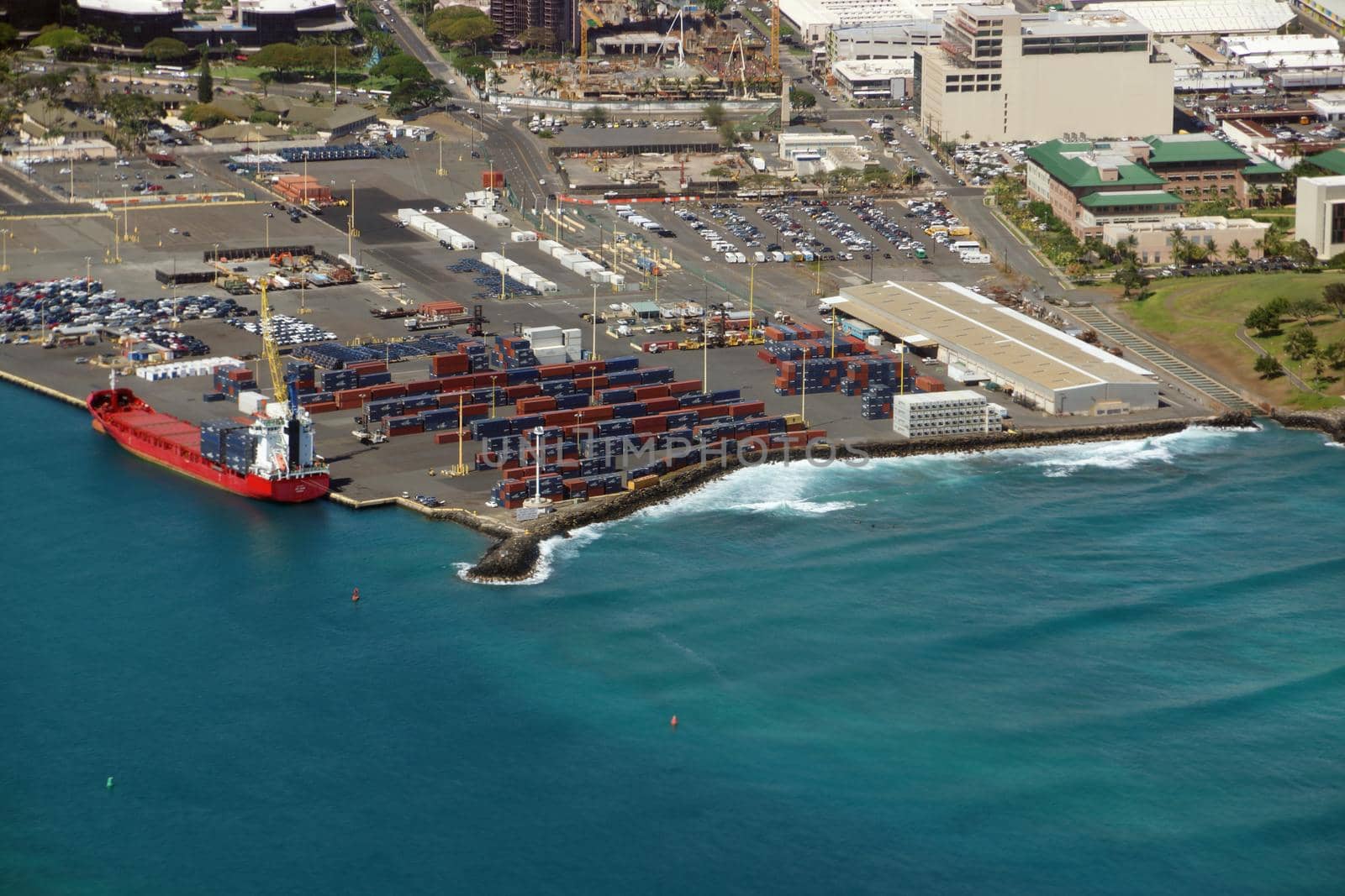 Honolulu - June 26, 2015:  Aerial of Cargo Boat being unloaded on Pier 1, Re-Use Hawaii, Medical College, and Water Treatment Plant along the coast at the harbor entrance of Oahu, Hawaii.