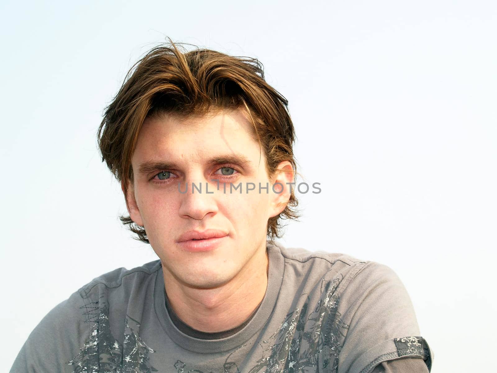 Portrait head shot of a handsome man twenty some, Actor Tony Wyban, with blue eyes and white background.