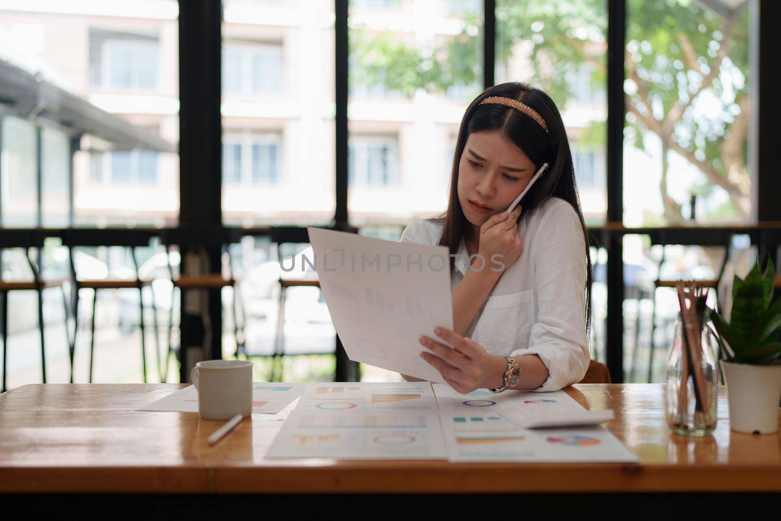 Image of Young woman with a cell phone working with paperwork. studying or working from home online concept