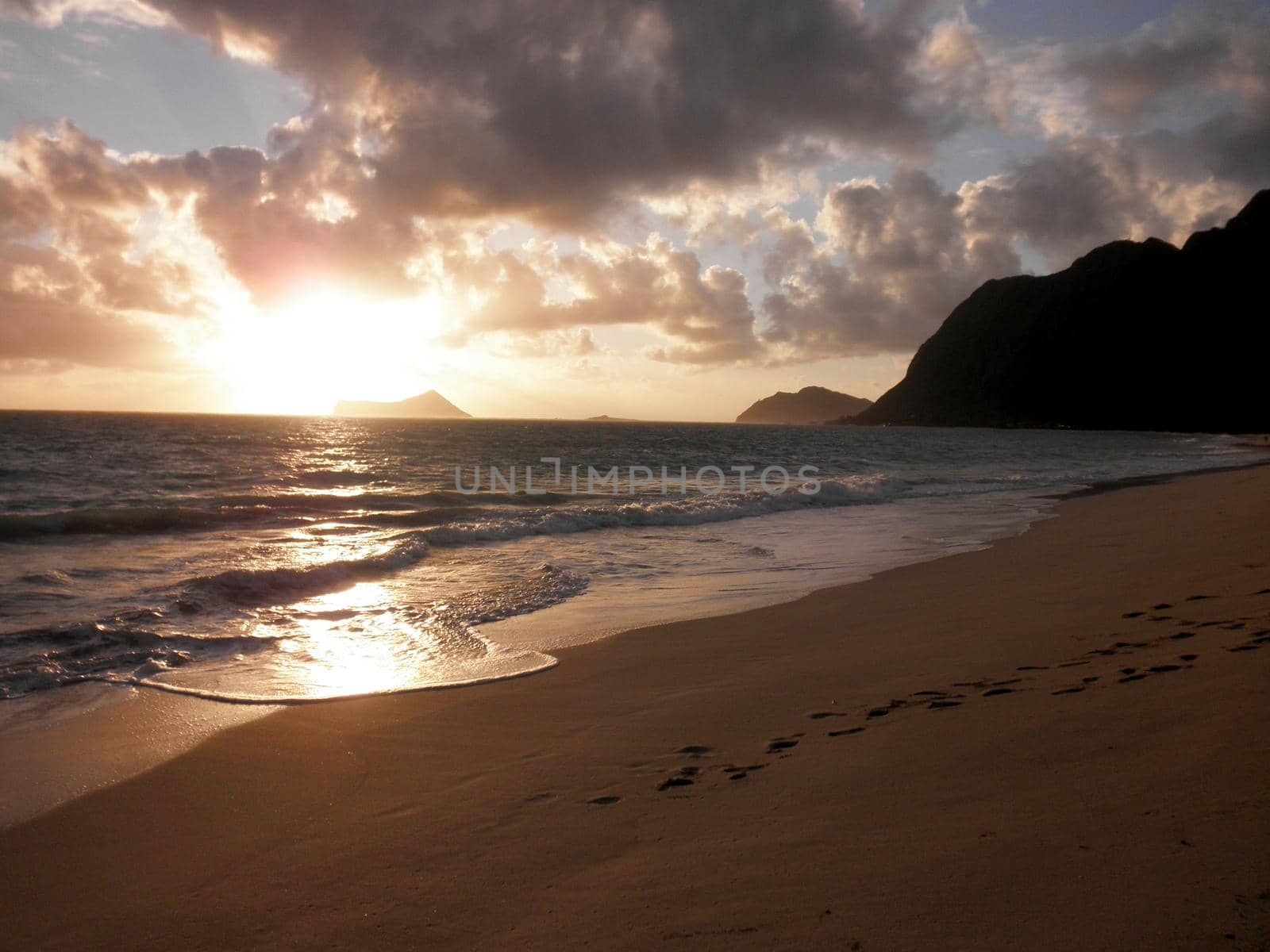 Early Morning Sunrise on Waimanalo Beach on Oahu, Hawaii over Rabbit Island by Rock Island bursting through the clouds. March 3, 2010.