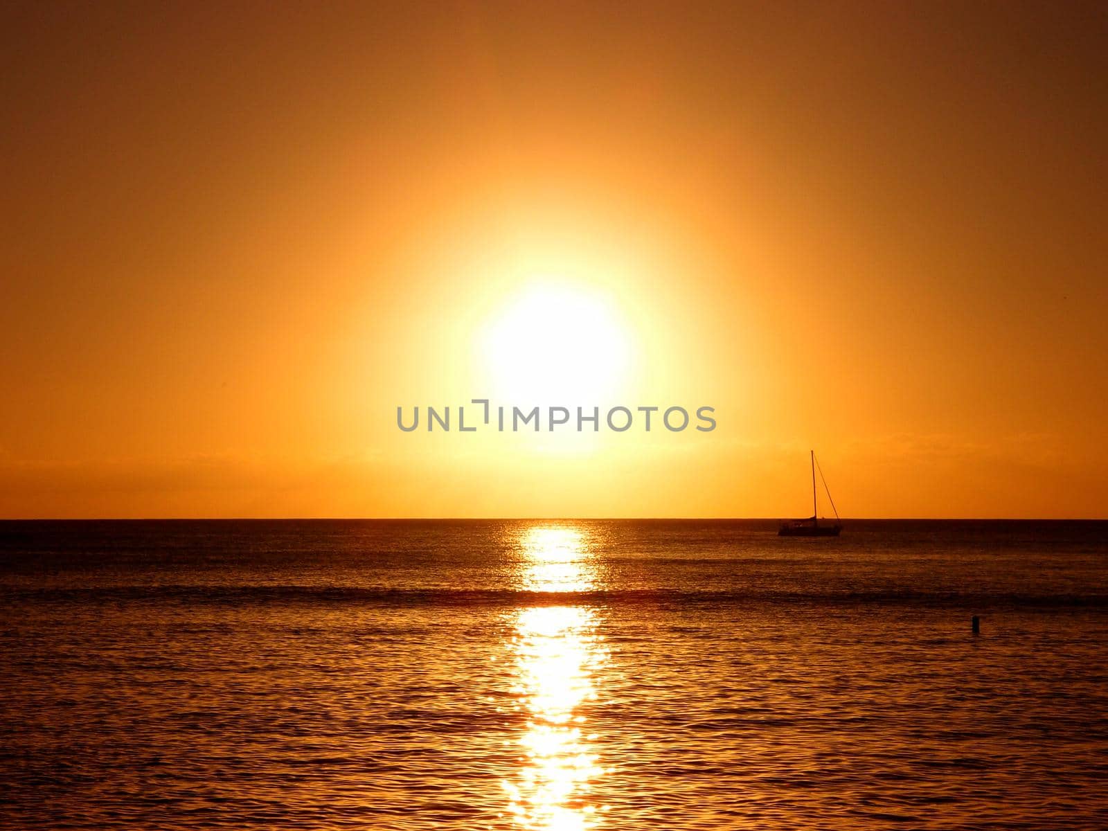 Sunset over the Pacific ocean reflecting on the water with boat off the coast of Oahu, Hawaii.