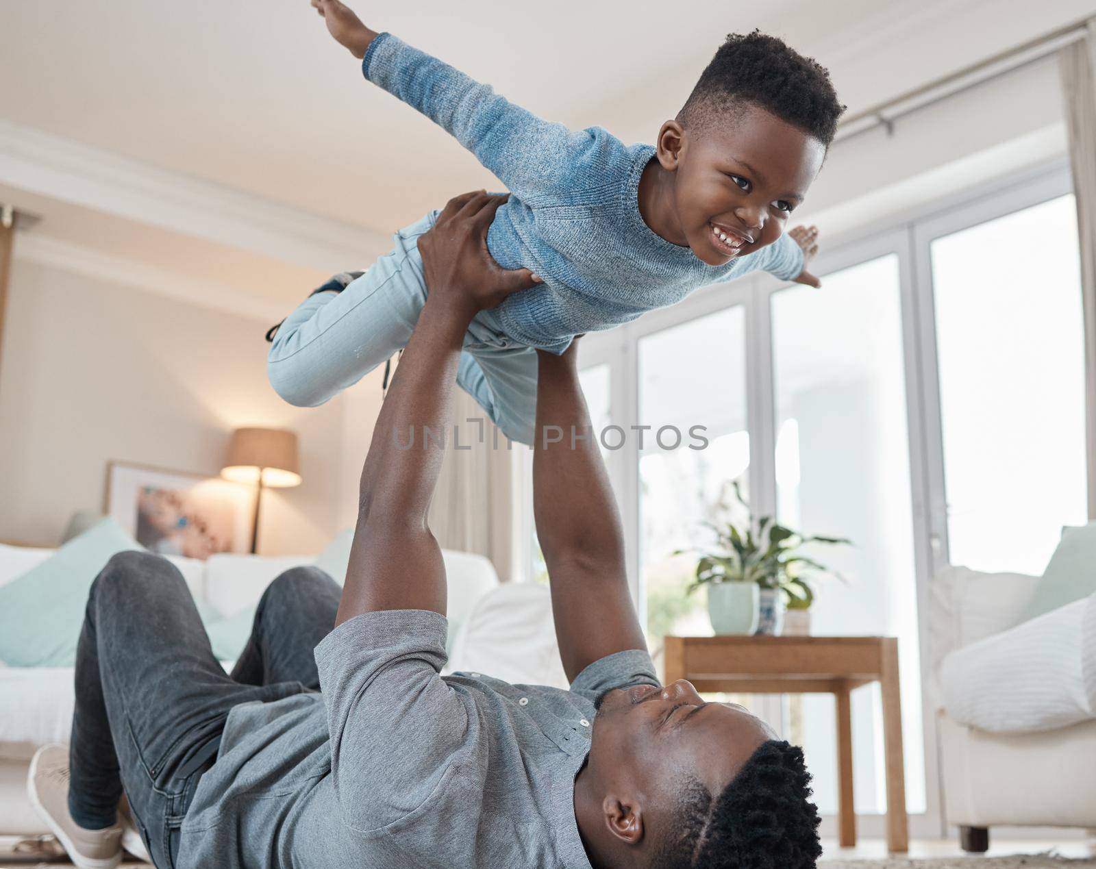 Defying the laws of gravity. a young father lying on the the living room floor and bonding with his son at home