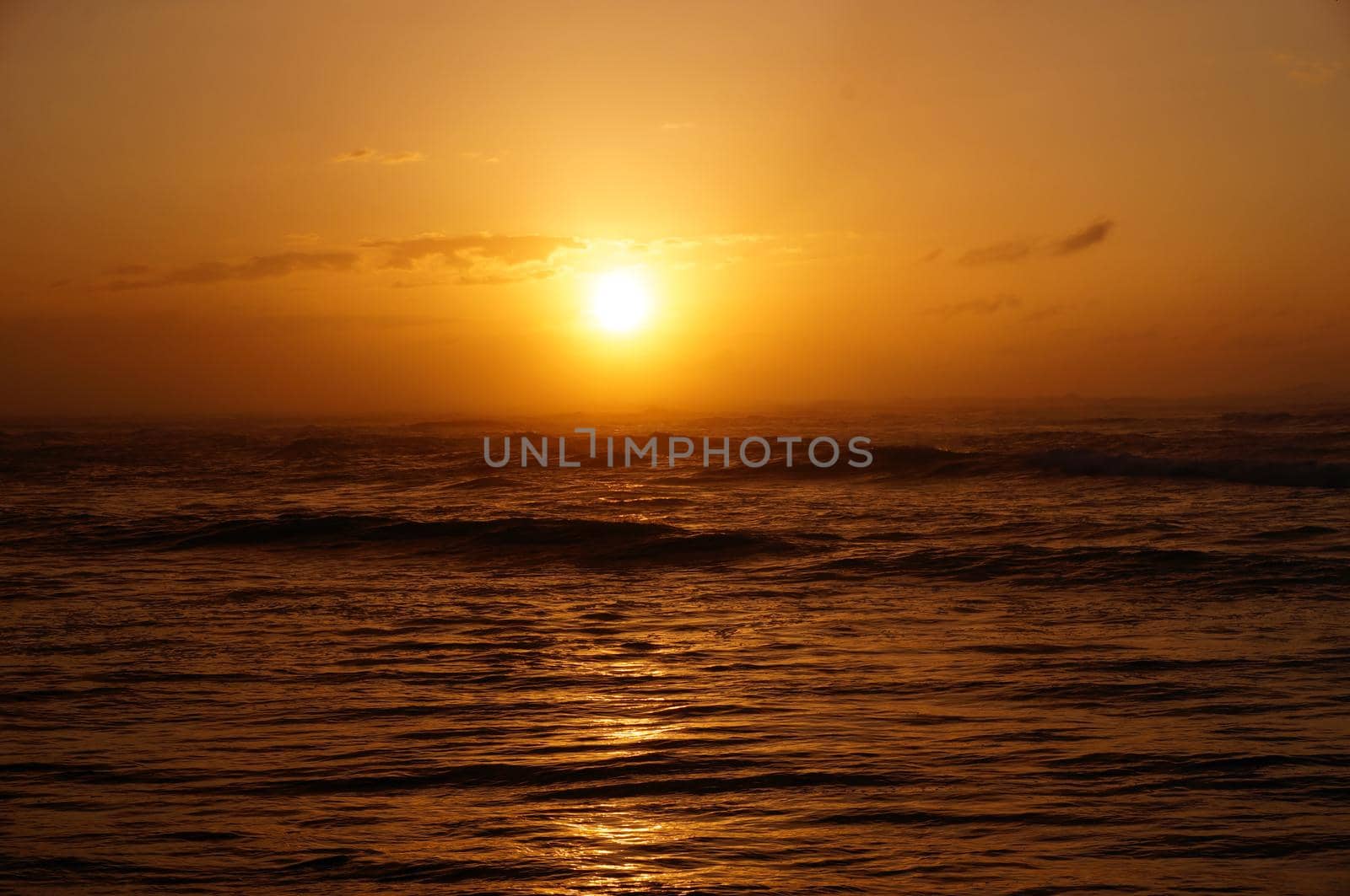 Sunset over the ocean with light reflecting on ocean waves moving  off North Shore with clouds on Oahu, Hawaii.