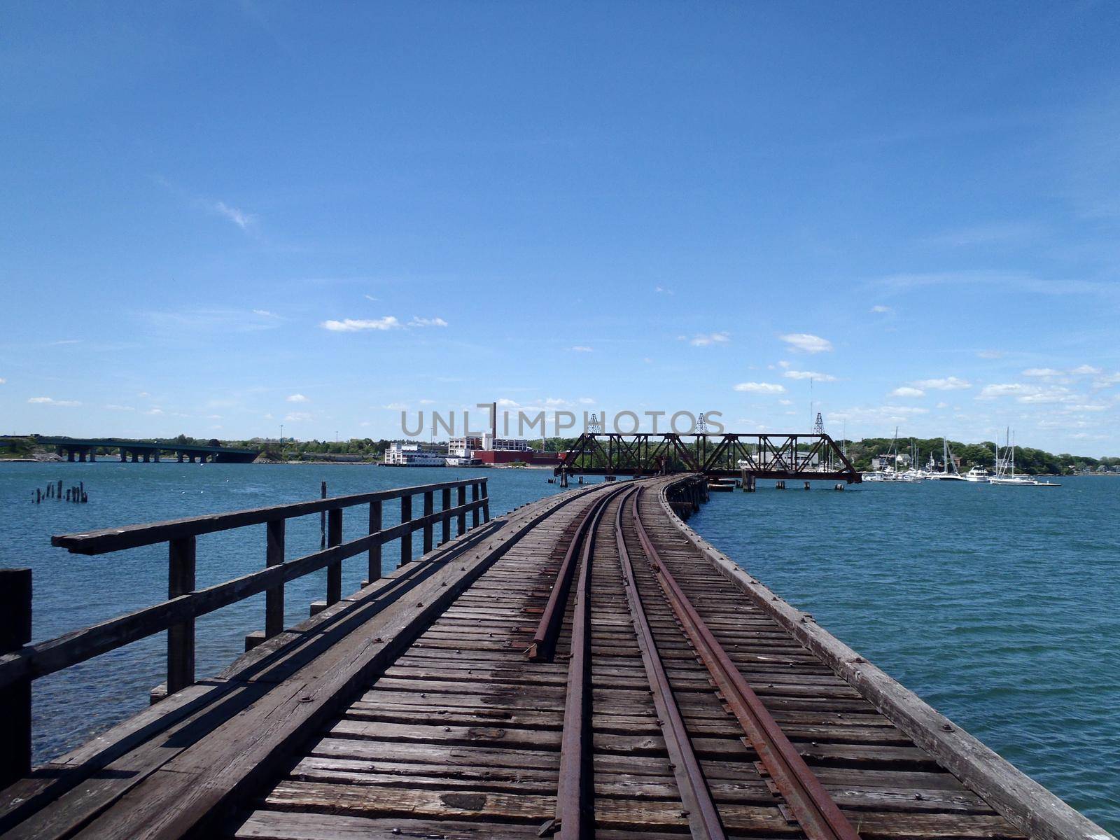 Railroad tracks on bridge across Back Cove in Portland, Maine during the day.