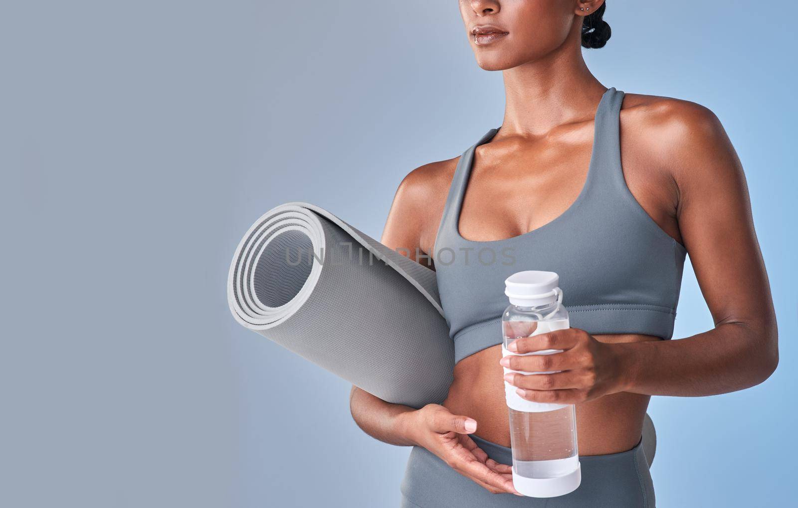 Better begins today. Studio shot of a fit woman drinking bottled water against a grey background