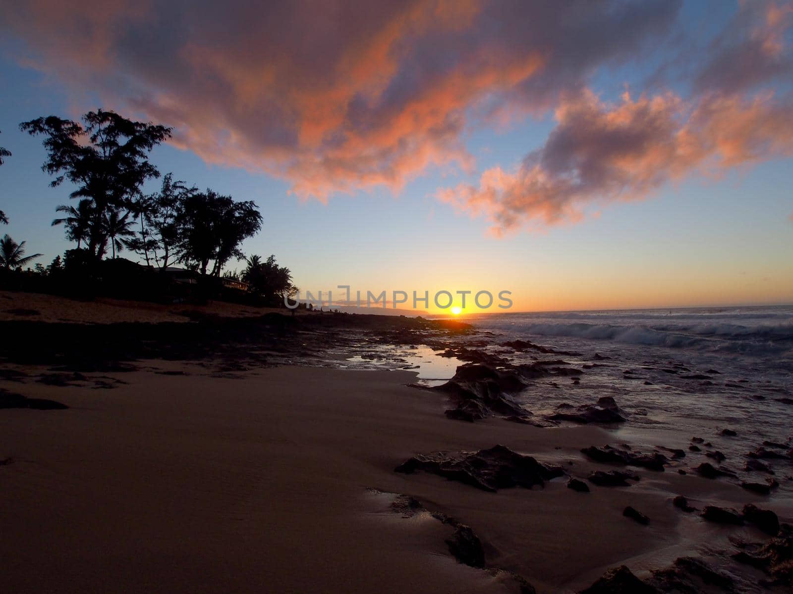 Beautiful Sunset over the ocean and beach with waves moving to shore on the Sunset Beach on the North Shore of Oahu.    