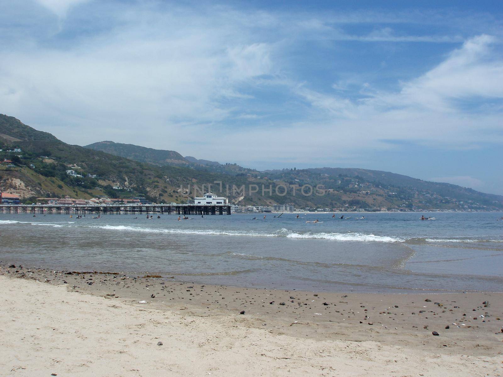 Malibu Lagoon State Beach and Malibu Pier with people surfing in the ocean.