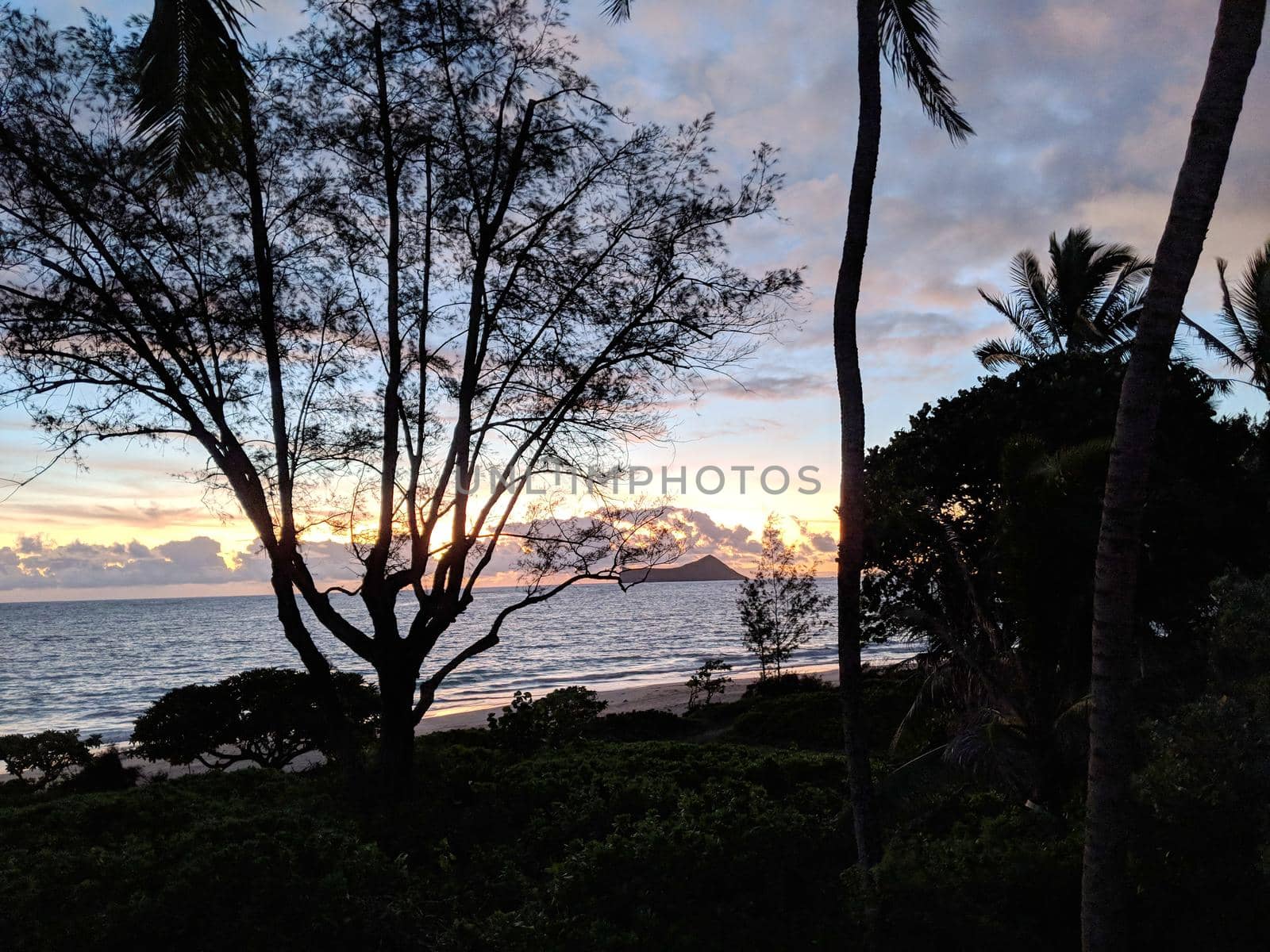 Early Morning Sunrise on Waimanalo Beach on Oahu, Hawaii over ocean by Rabbit and Rock Island bursting through the clouds. 