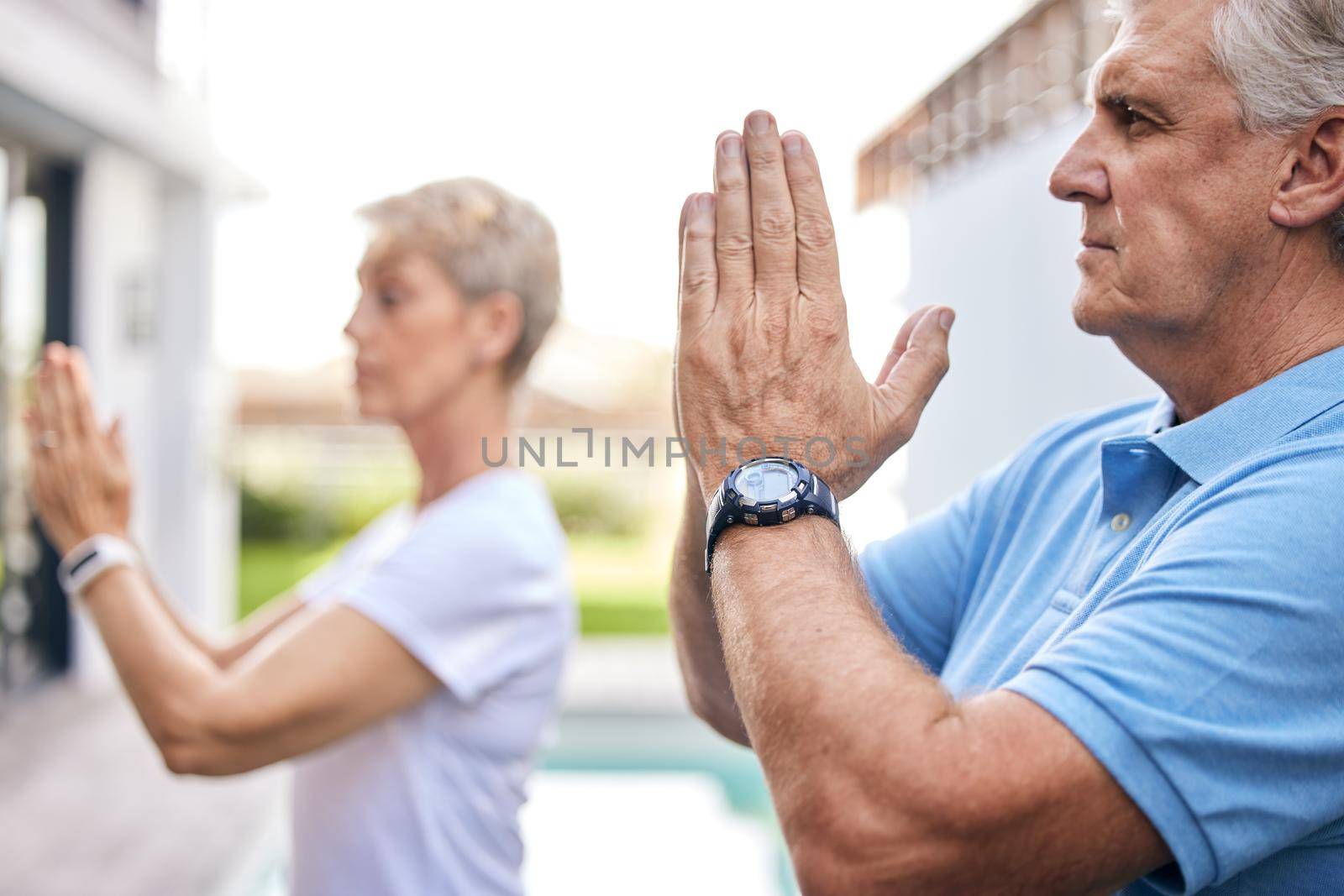 Calm is the best way to live. a mature couple meditating together outdoors