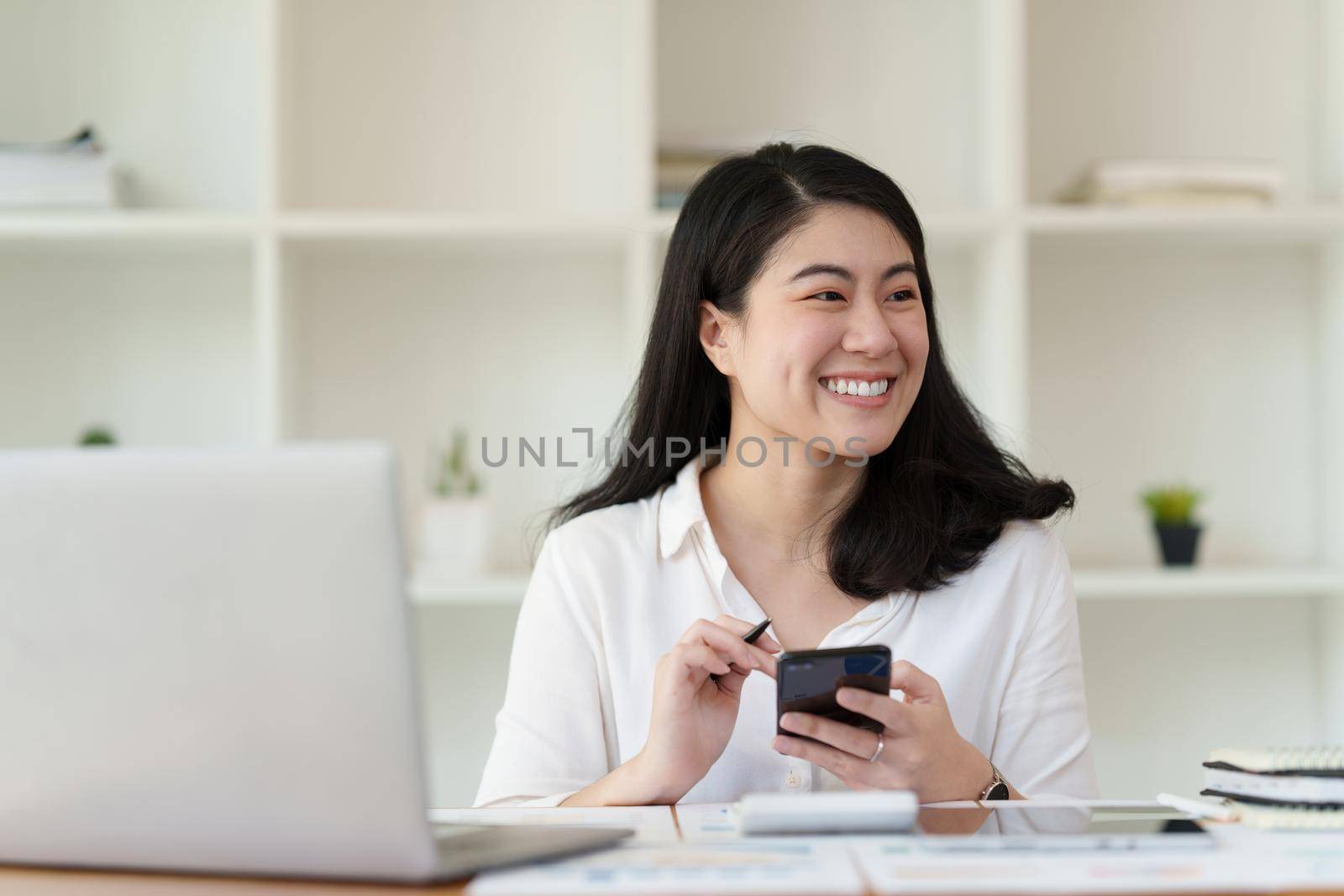 Happy business woman using smart phone and working at office