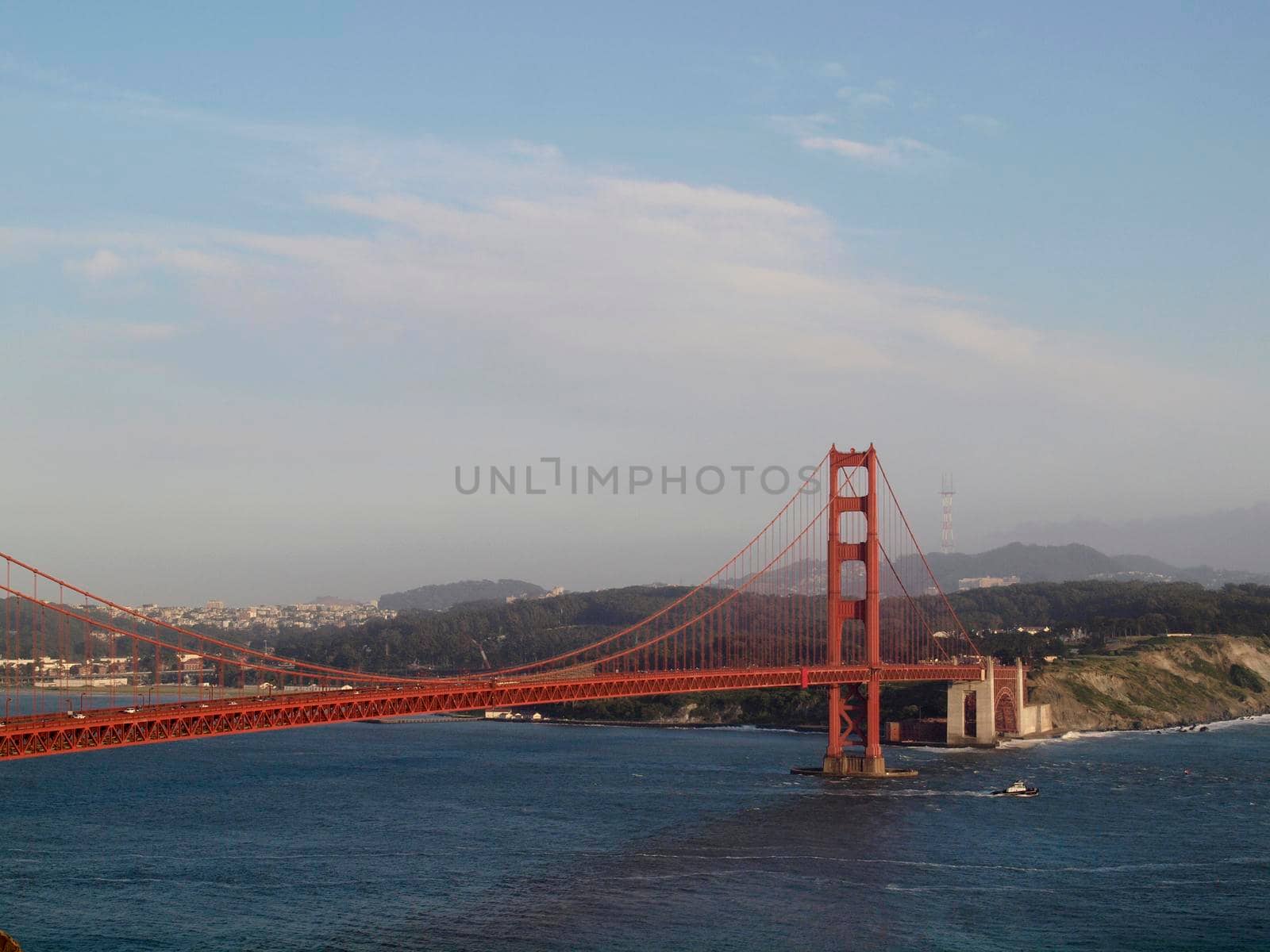 Tug boat sails under Golden Gate Bridge with San Francisco Cityscape, taken from the Marin Headlands hills.